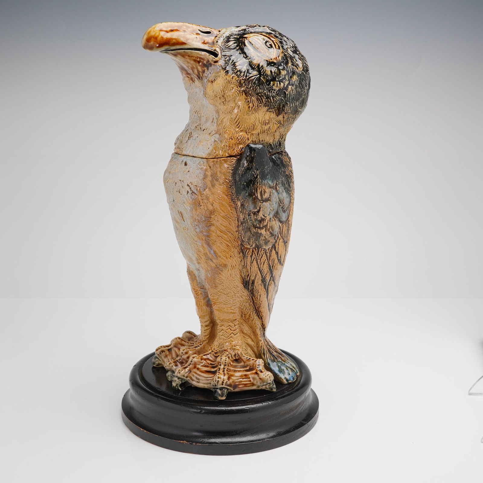 Martin Brothers Stoneware Jar with Cover, Wally Bird: A singular Martin Brothers salt-glazed stoneware lidded jar and cover, commonly known as a 'Wally Bird' or tobacco jar, mounted on a separate black-painted wooden plinth. The piece is modeled as an up