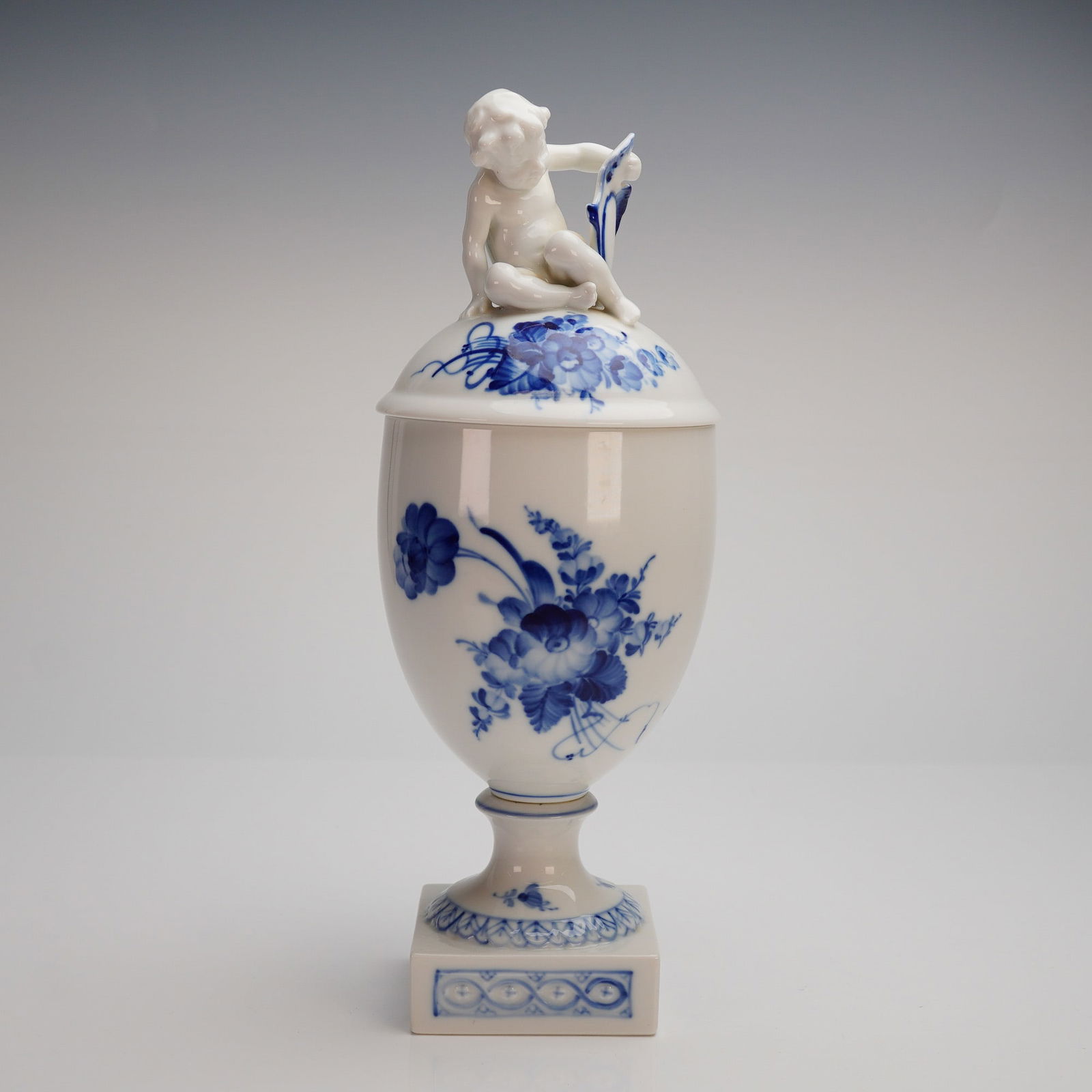 Royal Copenhagen Porcelain Lidded Urn, Blue Flower: A Royal Copenhagen porcelain covered urn-shaped vessel in the "Blue Flowers" pattern, model number 10/1754. The urn is executed in the neoclassical style, featuring a tapered body set upon a stepped,