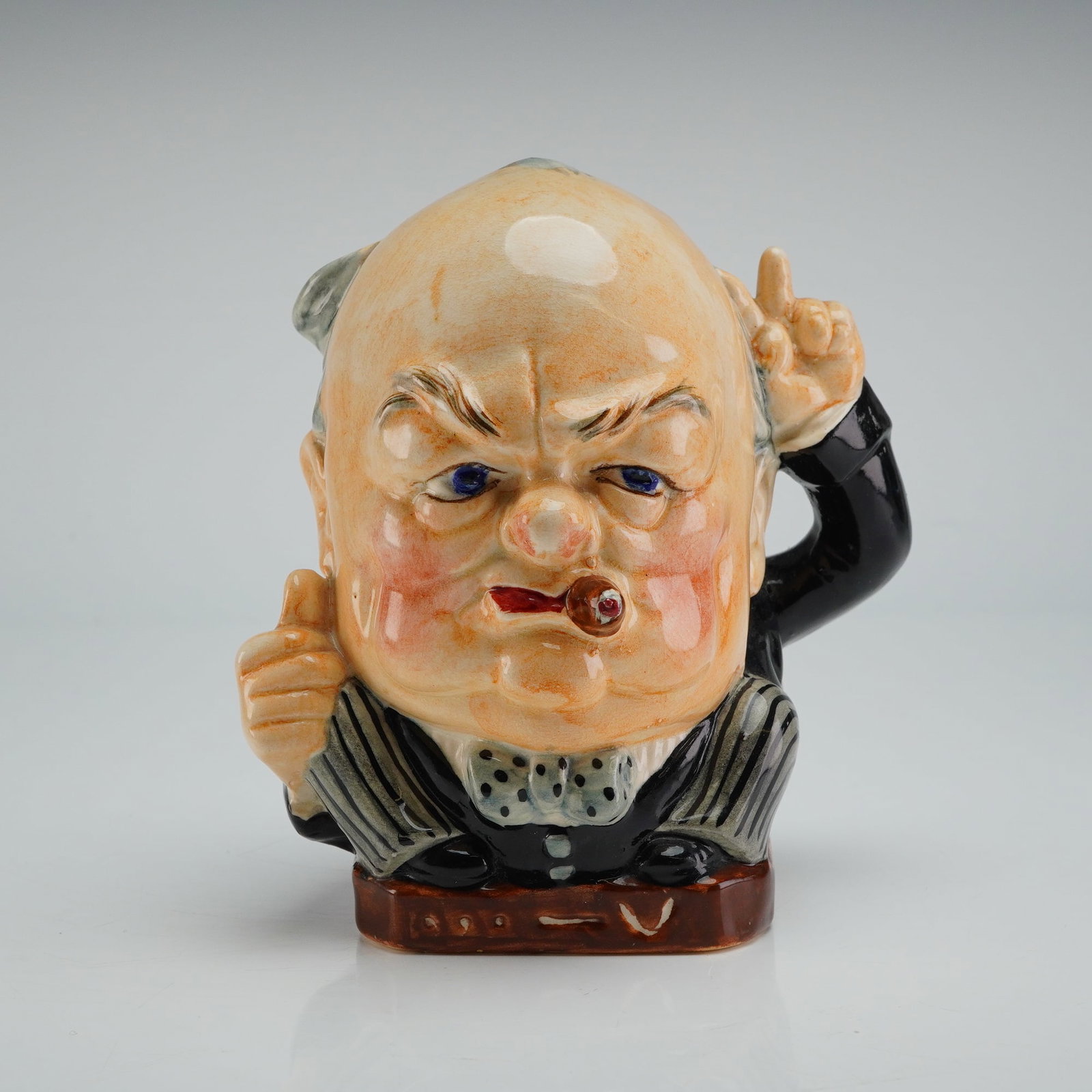 Burleigh Ware Winston Churchill Victory Small Character Jug: A Burleigh Ware Winston Victory Character Jug, depicting a figural caricature of Sir Winston Churchill. The small ceramic jug is glazed and hand-painted, showing Churchill with a ruddy complexion, bal