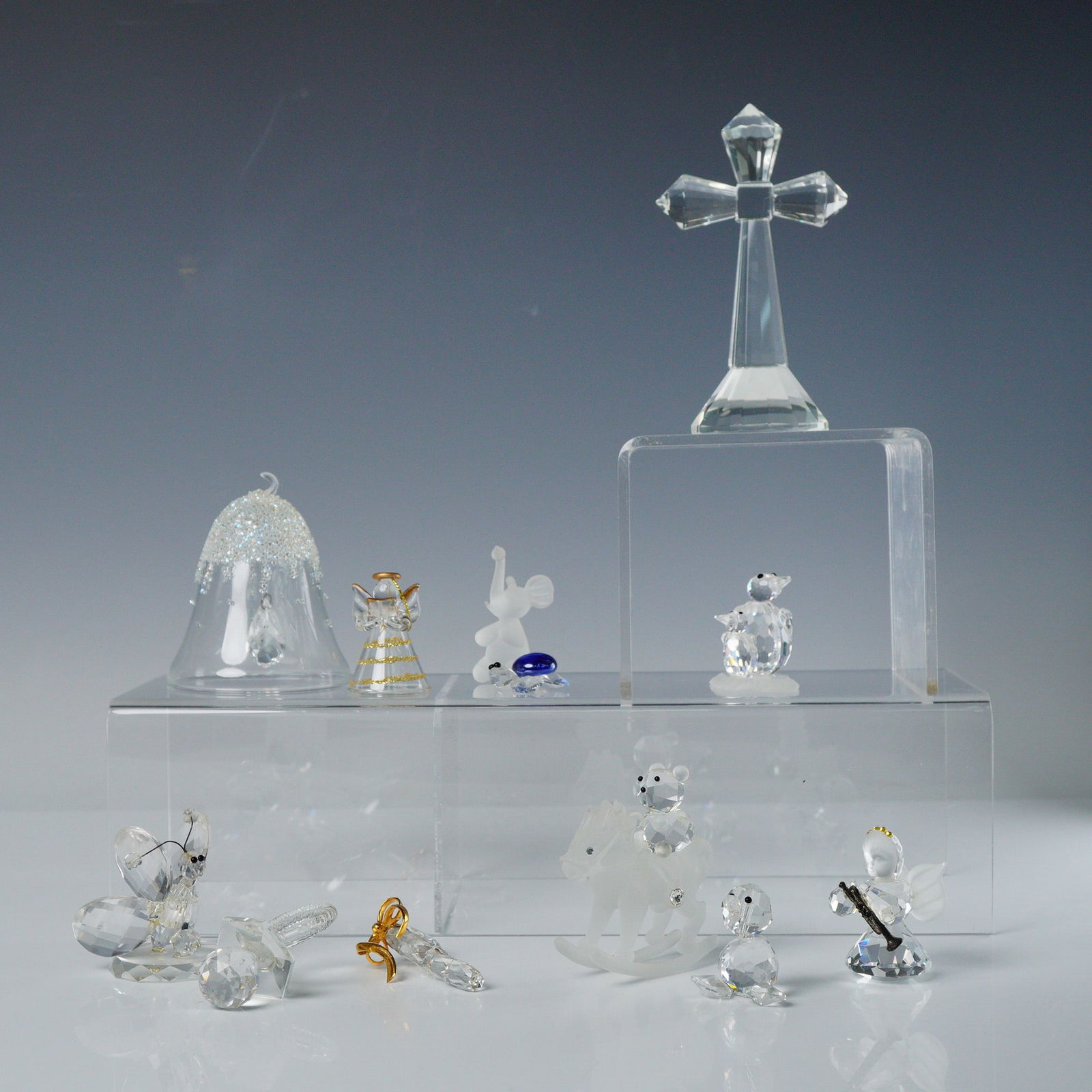 A Collection of 12pc Swarovski and Other Unmarked Crystal Figurines: A collection of 12 crystal and glass figurines, primarily executed in clear, faceted crystal, consistent with the style of Swarovski and Iris Arc. The collection includes various decorative objects an