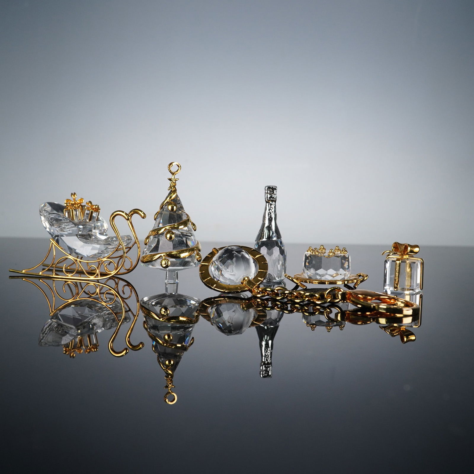 A Collection of Six Swarovski Crystal Memories Mini Figurines and Charms: A collection of six Swarovski Crystal Memories mini figurines and charms, featuring faceted clear crystal elements and gold-toned plated metal accents, with one piece utilizing rhodium-toned plating.