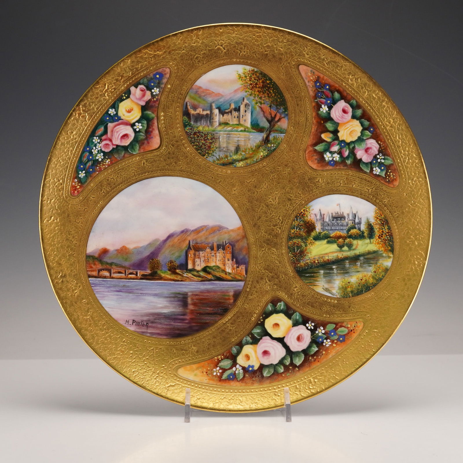 Coalport Gilt Bone China Plate by Manfred Pinter, Castle & Floral Vignettes: A Coalport gilt bone china cabinet plate, signed M. Pinter. This decorative plate features extensive gilding with a textured, embossed pattern. The front is adorned with a large central hand-painted v