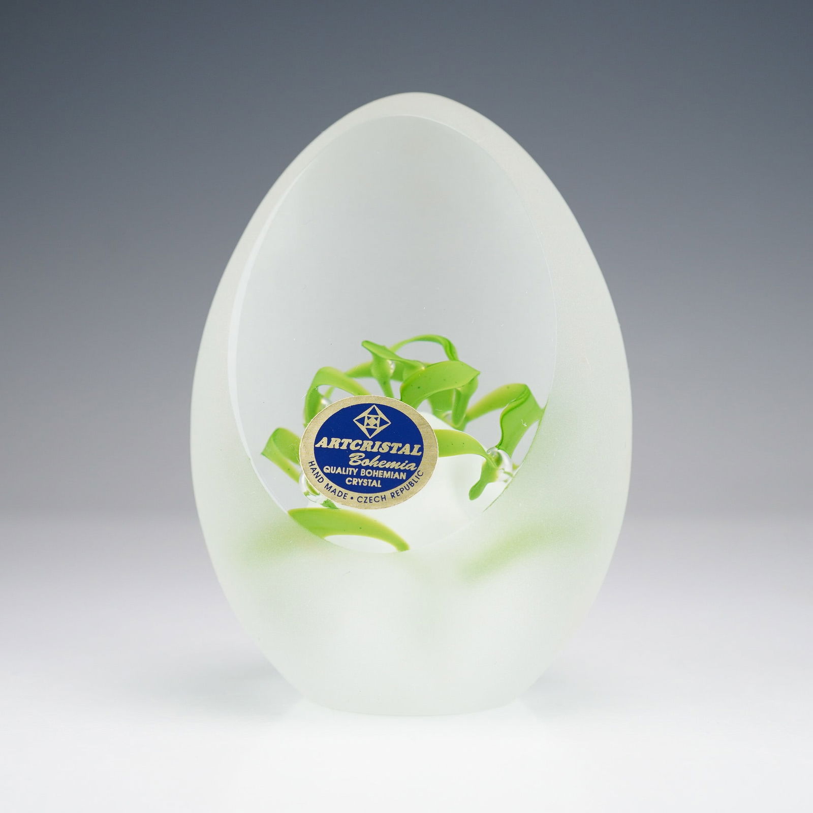 Artcristal Bohemia Frosted Crystal Egg Paperweight: A frosted Bohemian crystal ovoid form with internal clear cavity and swirling bright green elements. Label: ARTCRISTAL Bohemia, QUALITY BOHEMIAN CRYSTAL, HAND MADE " CZECH REPUBLIC. Etched ARTCRISTAL