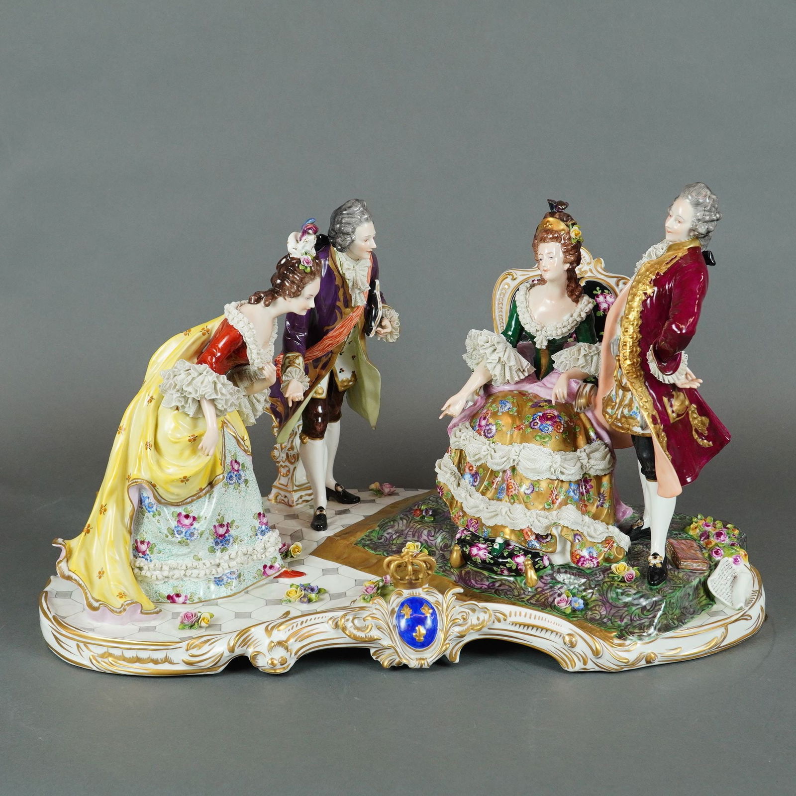 Volkstedt Polychrome Porcelain Figural Group Depicting a Court Scene: A single Volkstedt porcelain figural group, marked Volkstedt, executed in the 18th-century Rococo style. The group depicts a conversation or court scene featuring four figures: two standing gentlemen