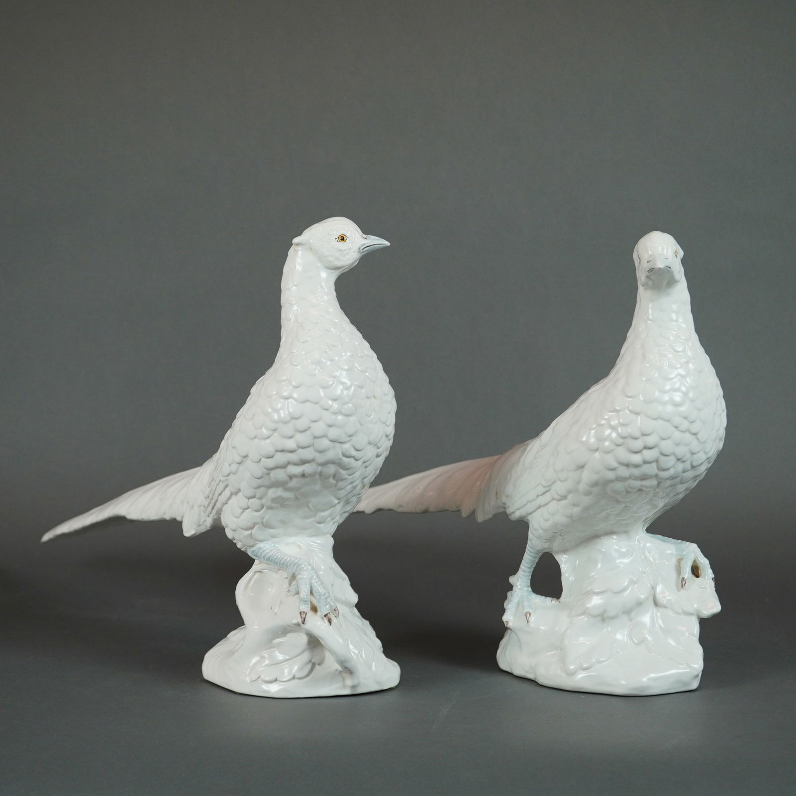 A Pair of Italian Glazed White Ceramic Pheasant Sculptures: A pair of vintage Italian glazed white pheasant sculptures, executed in molded ceramic with a high-gloss white glaze finish. The figures depict pheasants standing on molded rocky bases. Heavy molding