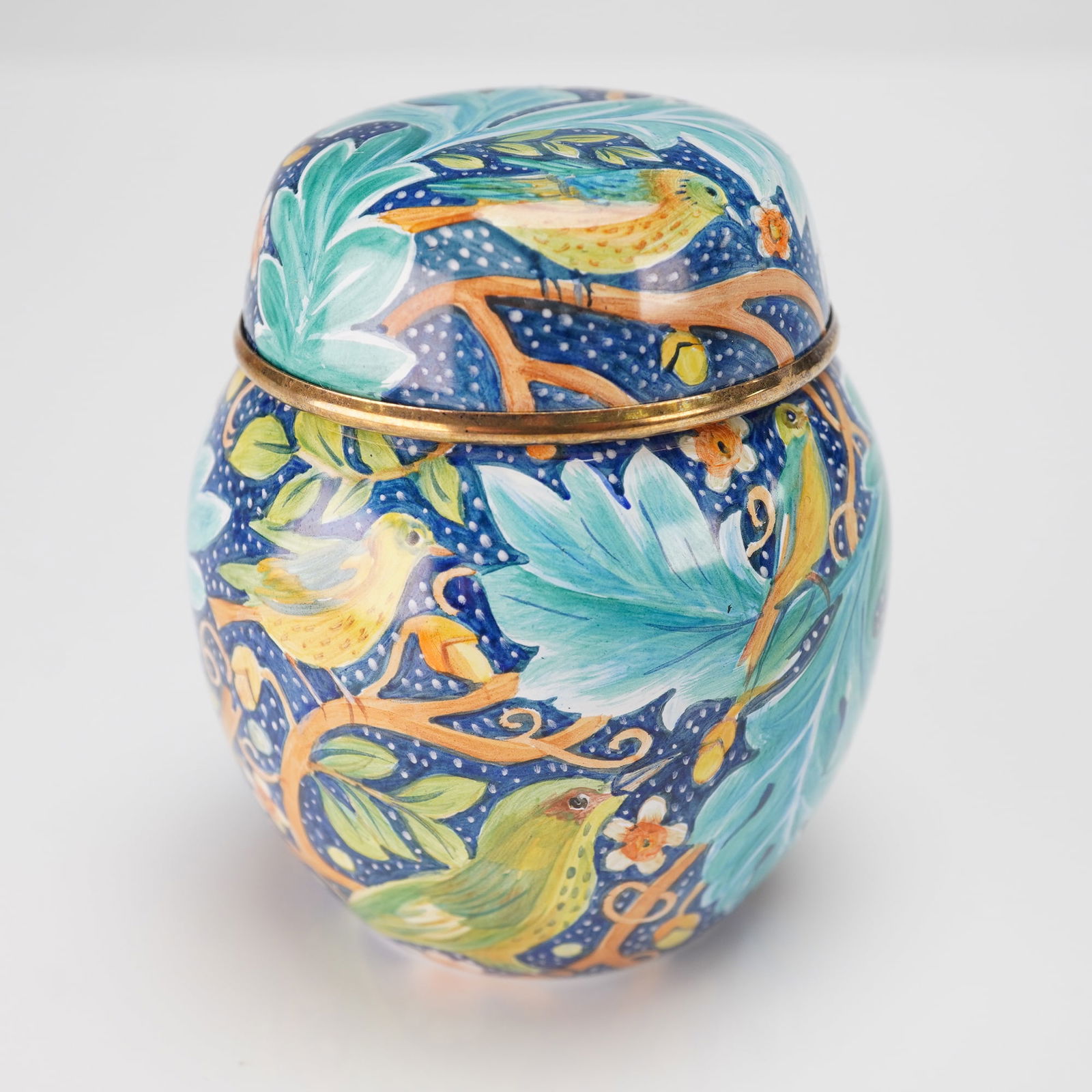 Elliot Hall Enamels Lidded Box, William Morris, Signed: A globular lidded box crafted from enameled metal with gold-toned metal rims. The box features a vibrant, intricate design in the Arts and Crafts style, inspired by William Morris, depicting various c