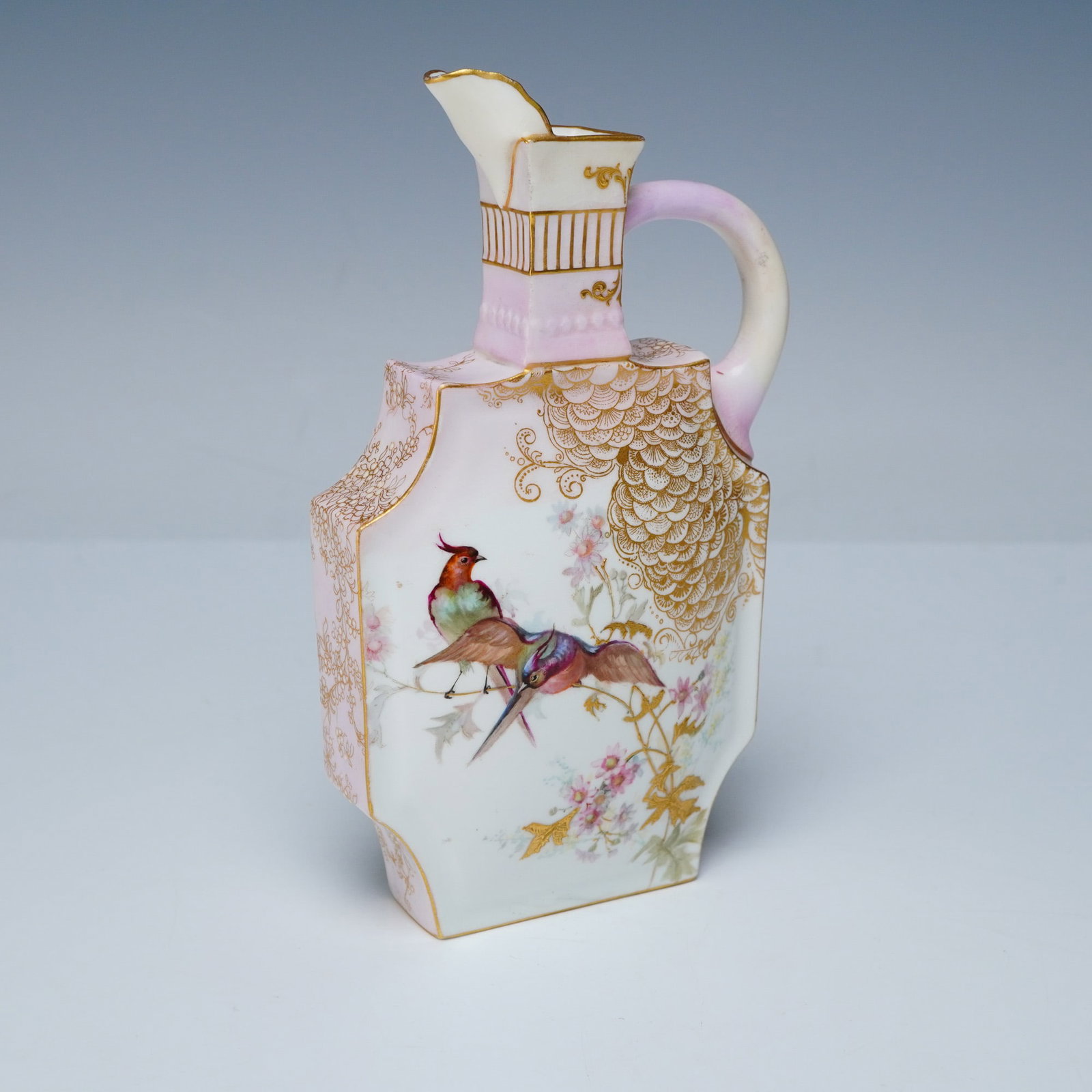 Doulton Burslem Art Deco Porcelain Pitcher: A very unusual vessel with a beautiful hand painted design. It features two birds perched on a branch on one side and a butterfly on the other. Set on a white and blush pink ground with intricate gilt