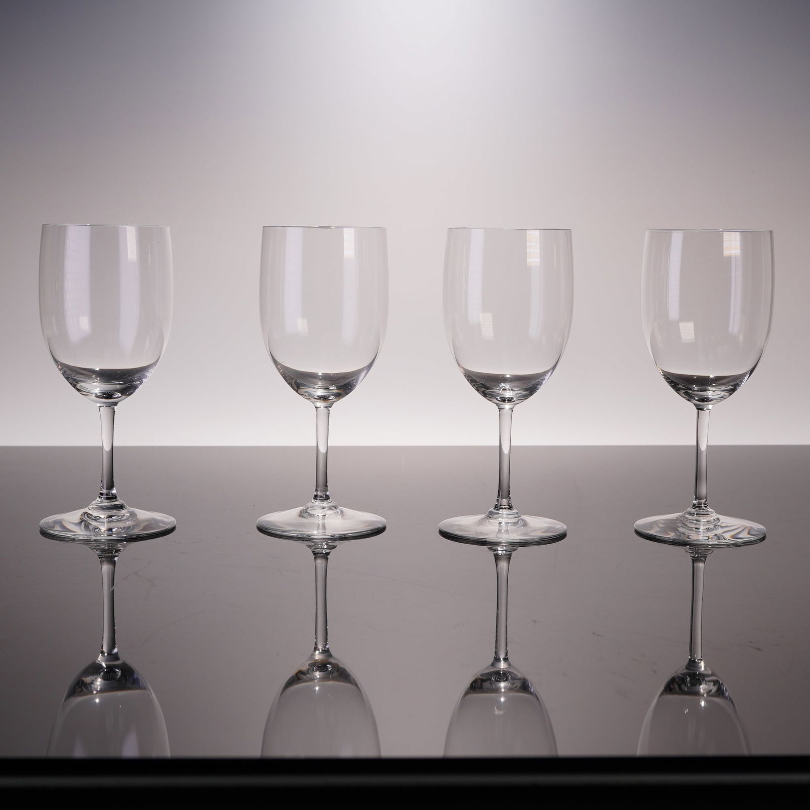 4pc Baccarat Claret Wine Glasses, Perfection: A set of four Baccarat 'Perfection' pattern claret wine glasses. Each glass features a classic, unadorned design with a gently curved bowl, a slender stem, and a flat circular foot. The clear crystal