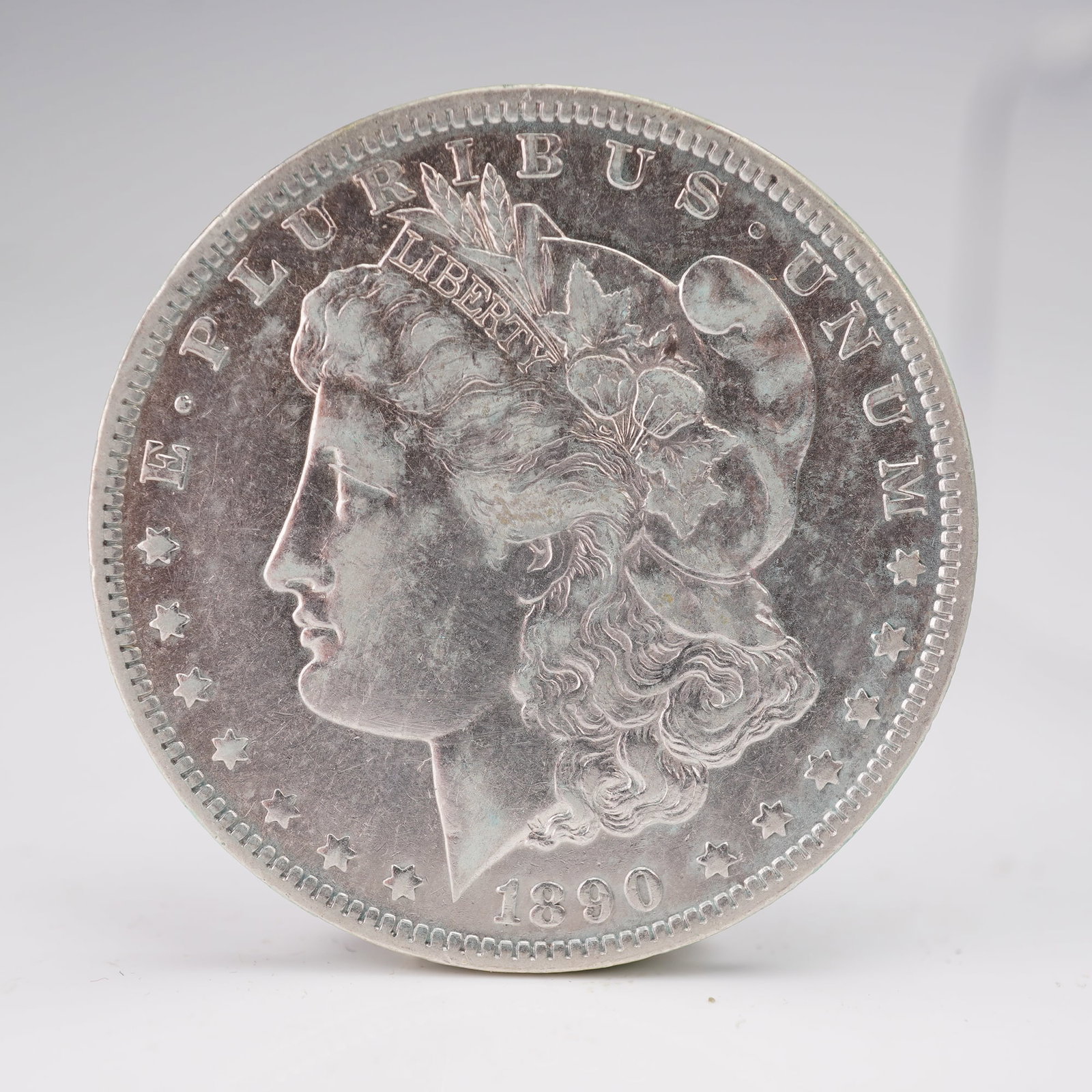 1890-O Morgan Silver Dollar: Struck at the New Orleans Mint, identifiable by the "O" mintmark on the reverse. The obverse features the profile of Lady Liberty wearing a Phrygian cap adorned with agricultural motifs, with the insc