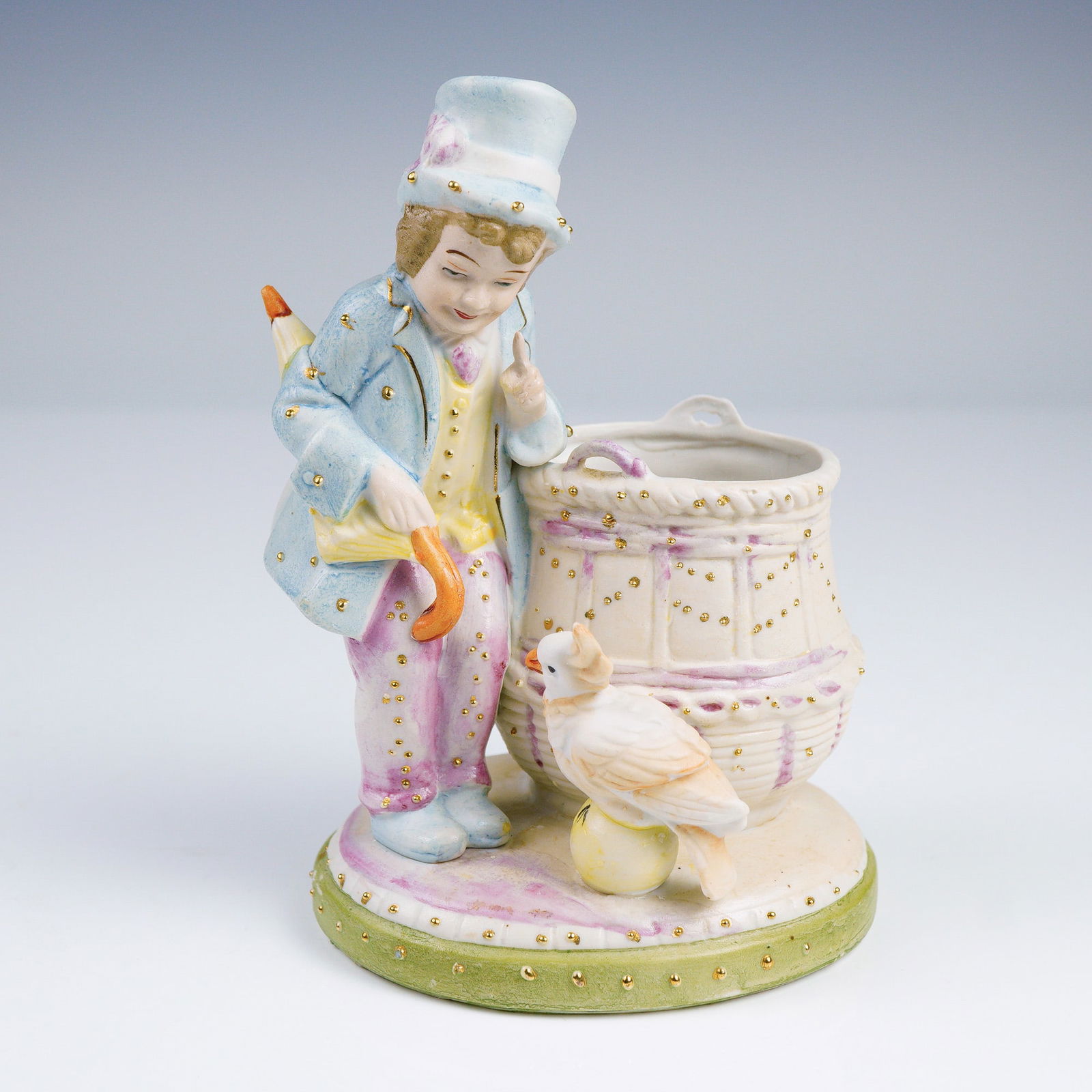 Antique Porcelain Figurine, Spill Vase with Boy with Cockatoo: This delightful 19th-century porcelain figural spill vase features a charming young boy dressed in a pastel blue frock coat, striped lavender trousers, and a sky-blue top hat, adorned with hand-applie