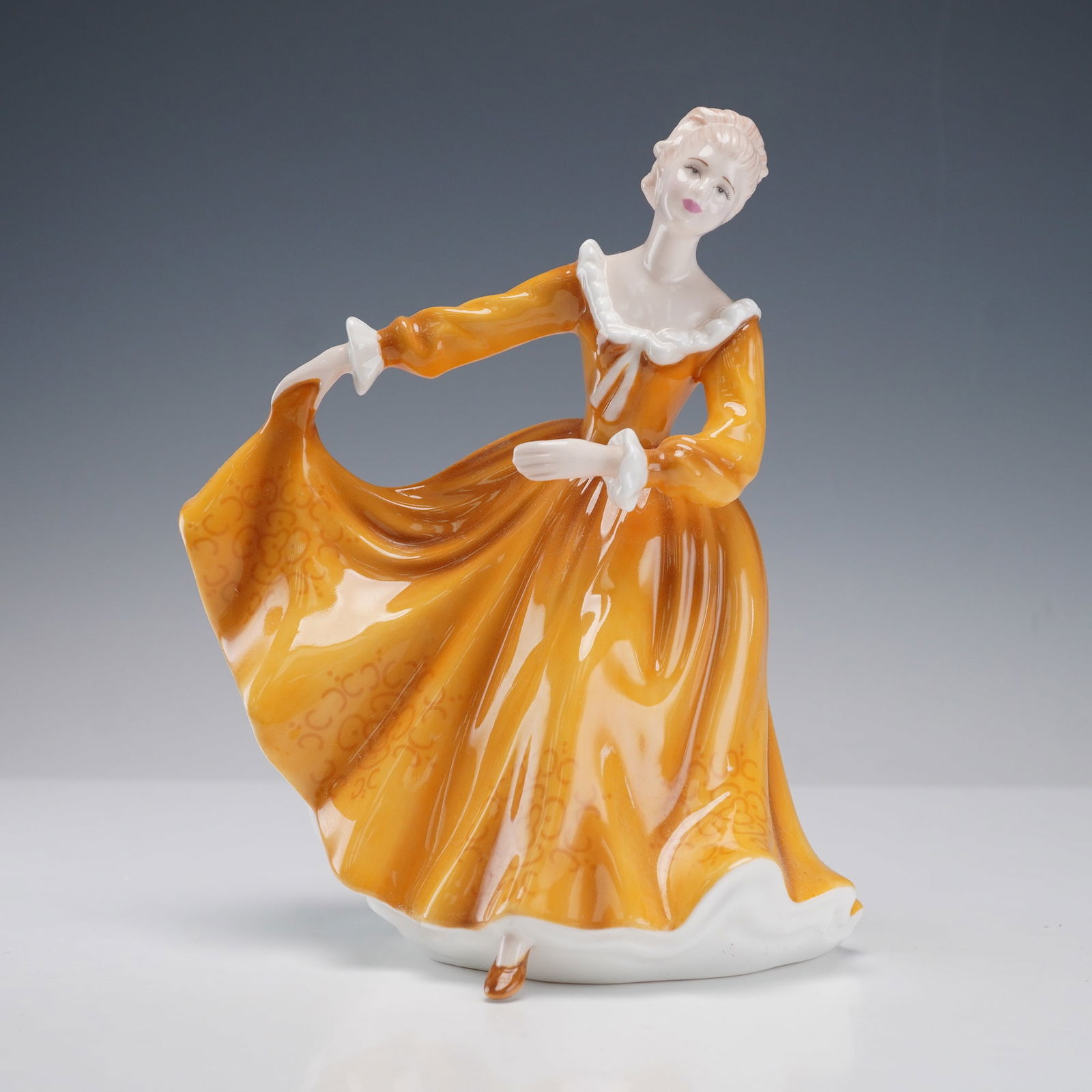 Royal Doulton Figurine, Kirsty HN4783: Royal Doulton porcelain figurine titled Kirsty from the Pretty Ladies Collection. The piece depicts a young woman in a flowing golden yellow gown with white ruffled trim, posed gracefully as she lifts