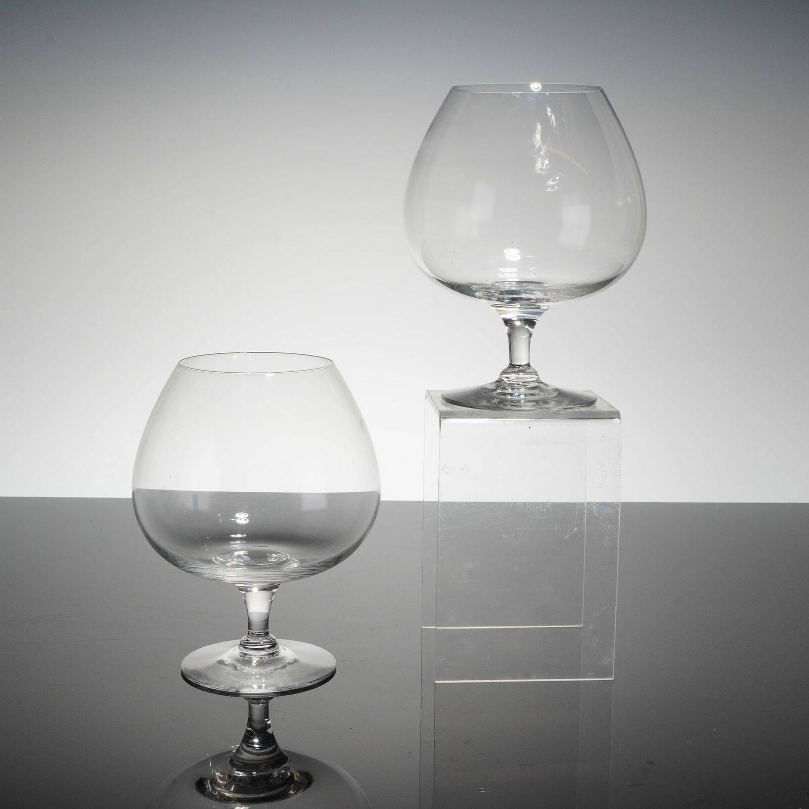 A Pair of Orrefors Hald Brandy Snifters: A pair of Hald patern brandy snifters designed by Edward Hald for Orrefors, Sweden. The glassware is crafted from clear colorless crystal or glass, featuring classic balloon-shaped bowls, short fi‚a