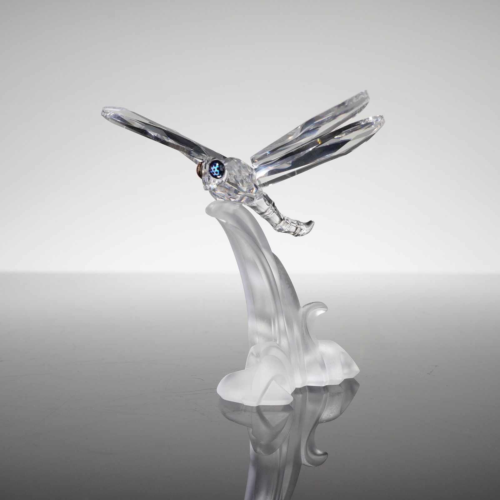 Swarovski Crystal Figurine, Dragonfly: A Swarovski Crystal Figurine, Dragonfly (190264), executed in clear, highly faceted crystal. The figurine depicts a dragonfly perched, featuring four clear faceted wings and small dark blue/black crys