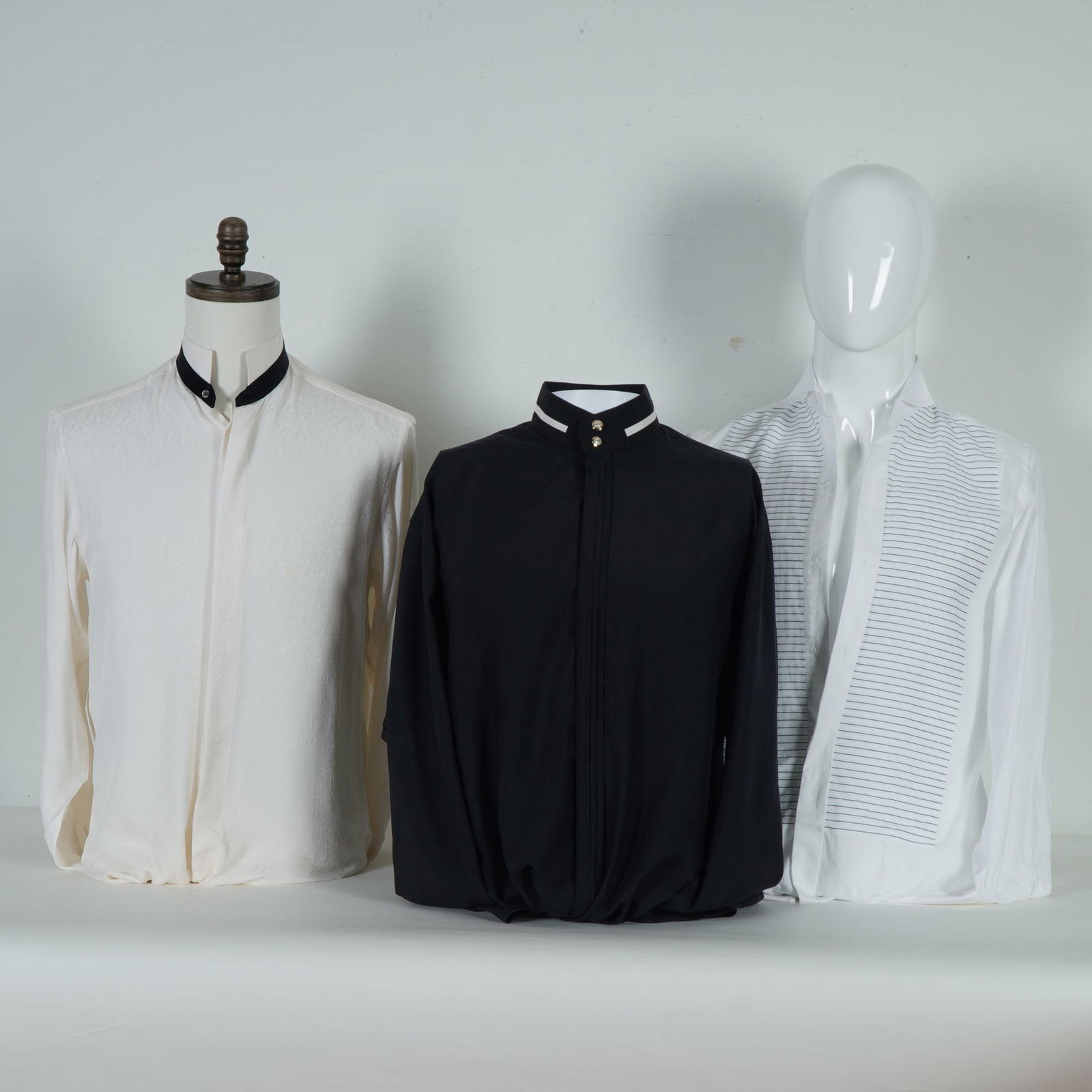 3pc Brioni, Xacus, and Bernini Couture Men Mandarin-Collar Shirts: A group of three refined men's mandarin-collar shirts comprising a cream jacquard-textured example by Xacus, Italy, featuring a subtle woven pattern and contrasting black collar trim; a black lightwei