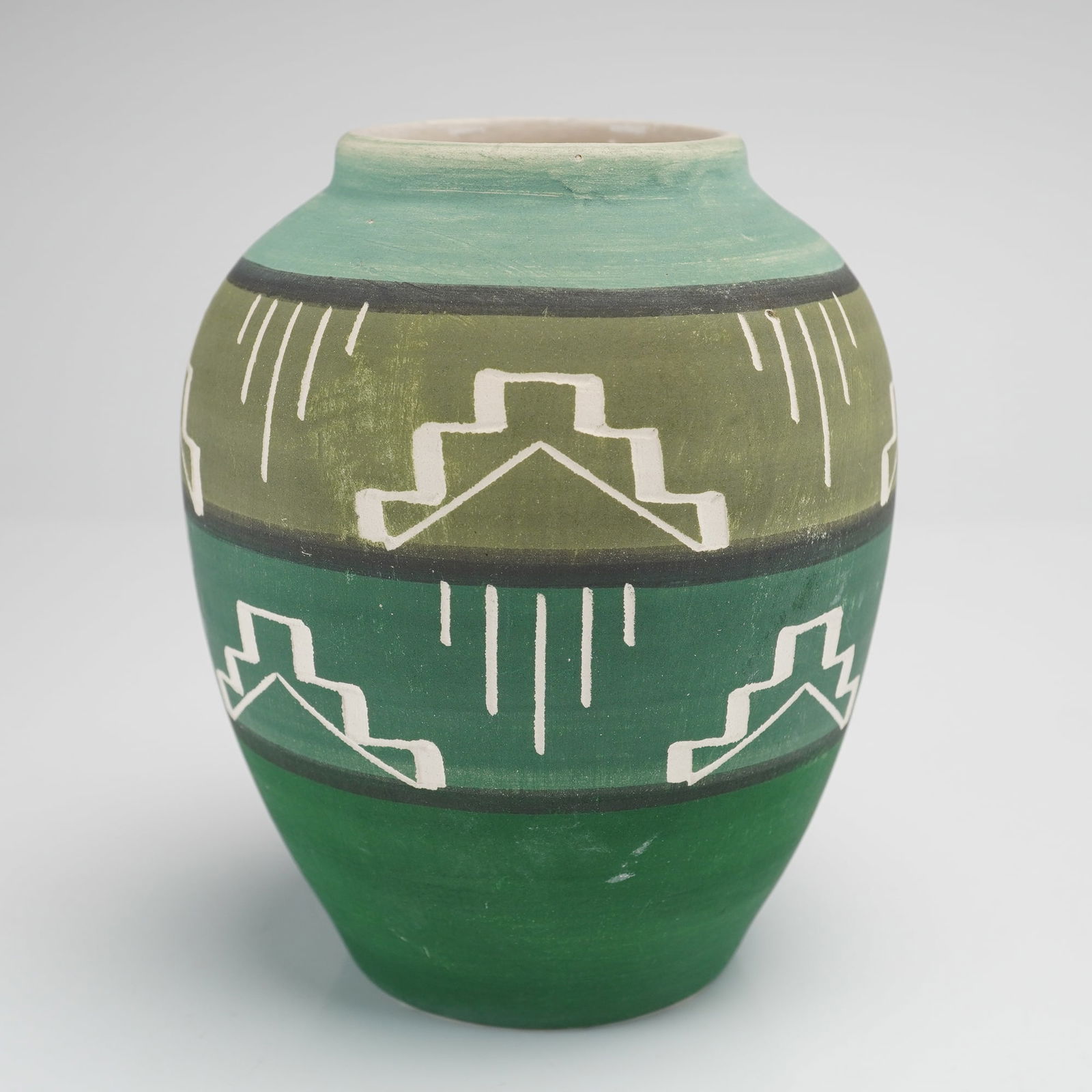 Signed Native American Sioux Art Pottery Vase: A single Native American Sioux Art Pottery vase, featuring a bulbous body and a restricted neck. The earthenware body is decorated with hand-painted matte slip in horizontal bands of various green ton