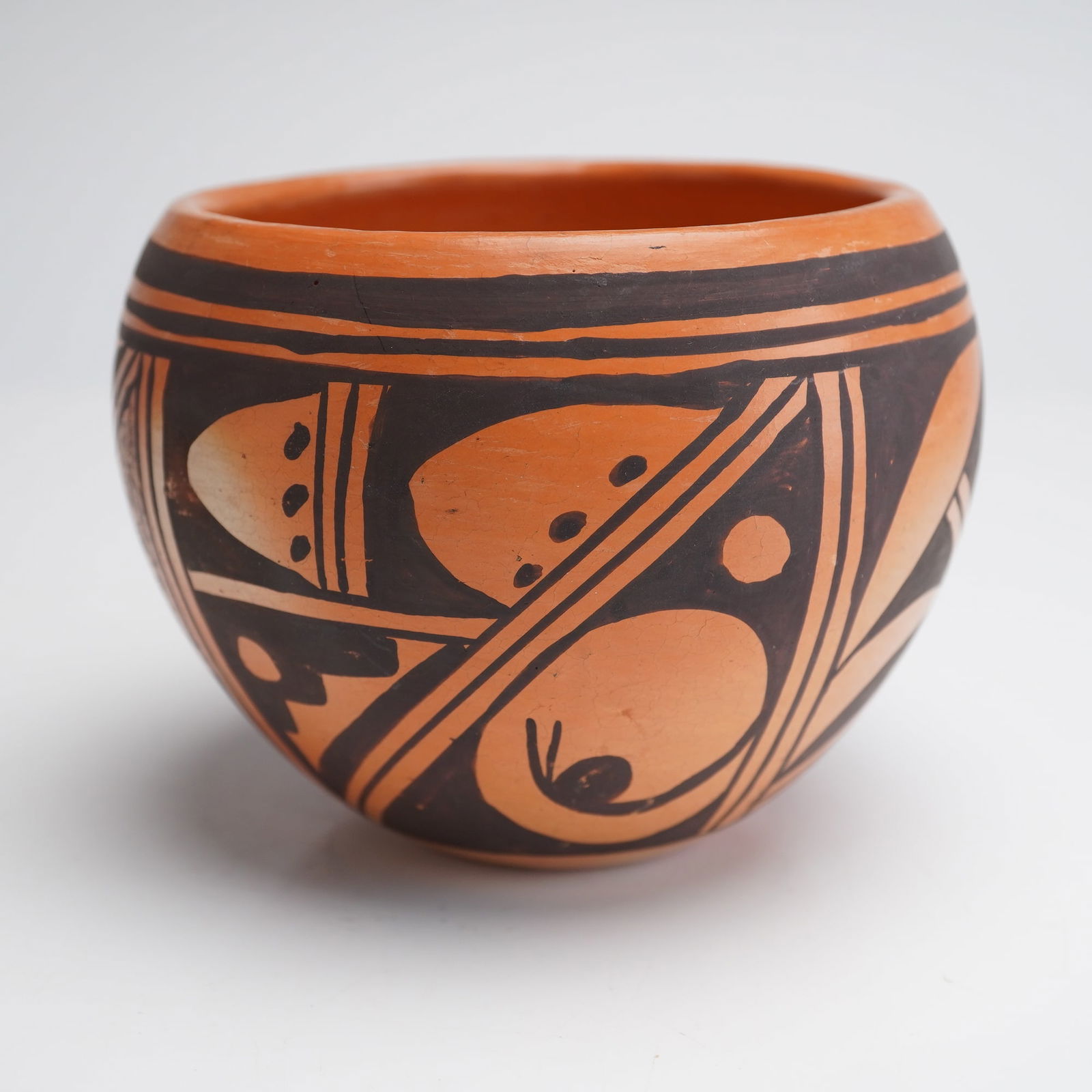 Vintage Hopi Pottery Bowl Signed: A vintage Native American Hopi Pottery Bowl, constructed of hand-coiled earthenware terracotta clay. The vessel features a rounded, globular body and a wide rim, executed in a traditional black-on-red