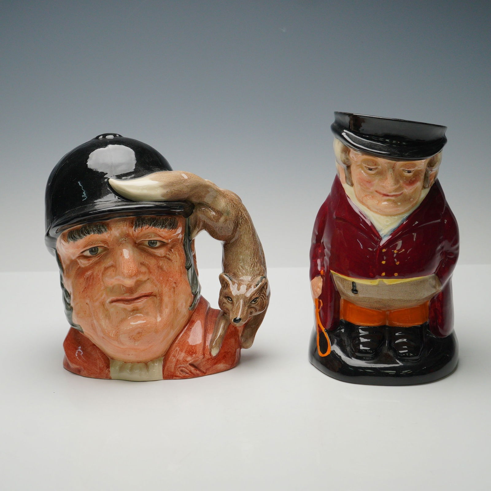 2pc Royal Doulton LG Character Jug-Gone Away D6531 & LG Toby The Huntsmen: Two-piece grouping of Royal Doulton jugs. The first, Gone Away D6531, designed by Gary Sharp, depicts a huntsman wearing a black riding helmet, with a fox head as the handle and Gone Away! inscribed t
