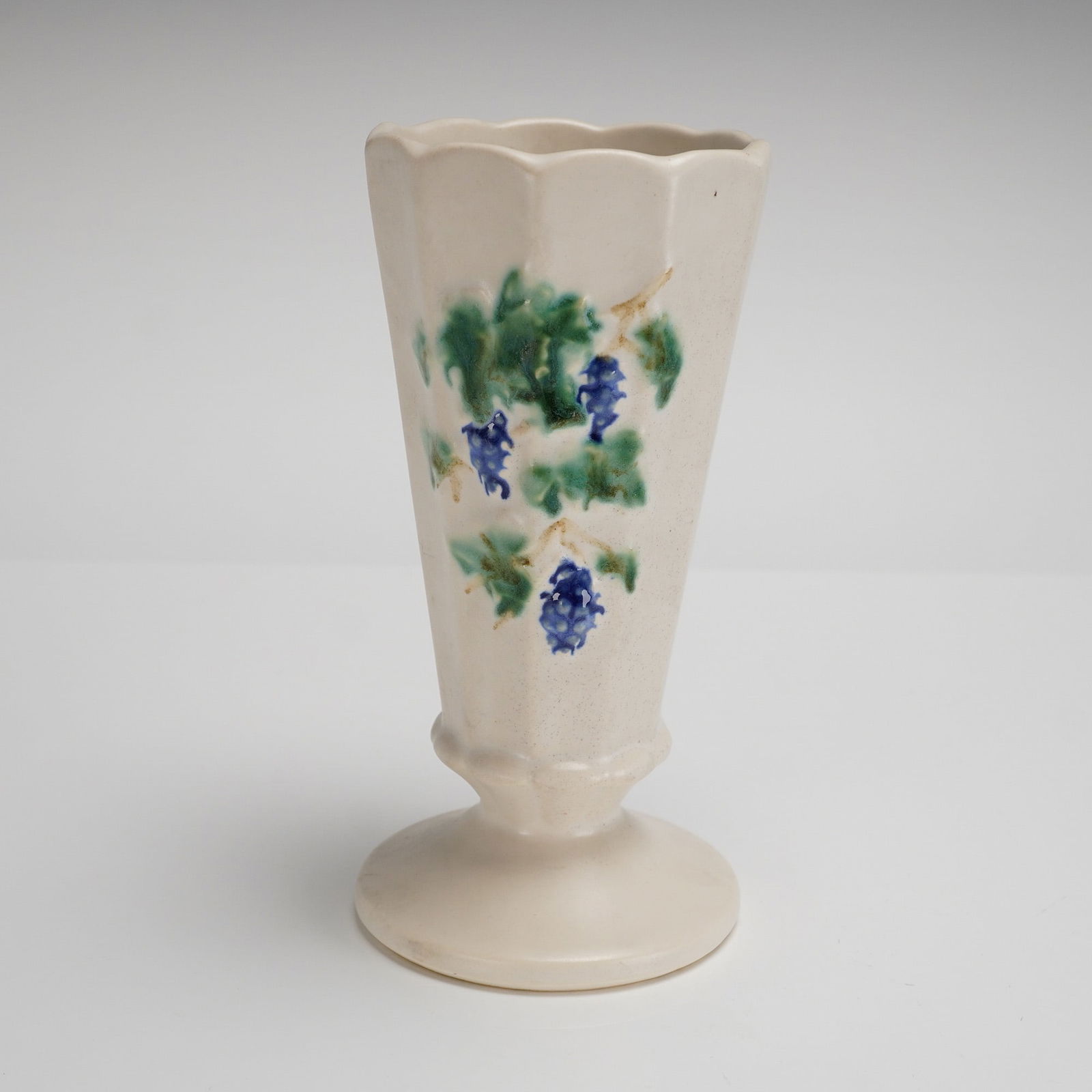 Vintage McCoy Pottery Grapes Paneled Pedestal Vase: A vintage McCoy Pottery Grapes Paneled Vase, attributed circa 1962 based on market consensus and user-provided keywords. The ceramic pedestal vase features a fluted or paneled conical body set upon a