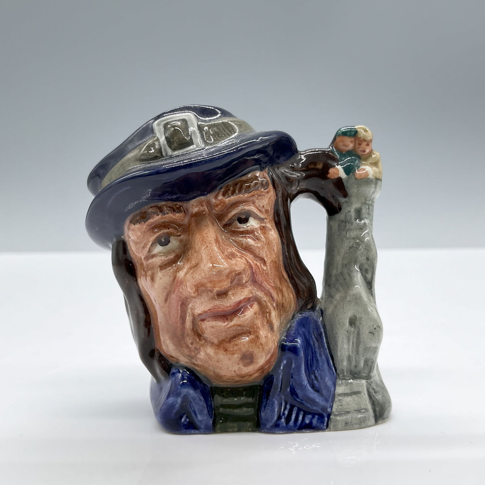 Gulliver D6566 - Mini - Royal Doulton Character Jug: Dark blue and grey hat; blue jacket; grey handle. Royal Doulton backstamp. Artist: David B. Biggs Issued: 1962 - 1967 Dimensions: 2.75"L x 2"W x 2.75"H Country of Origin: England