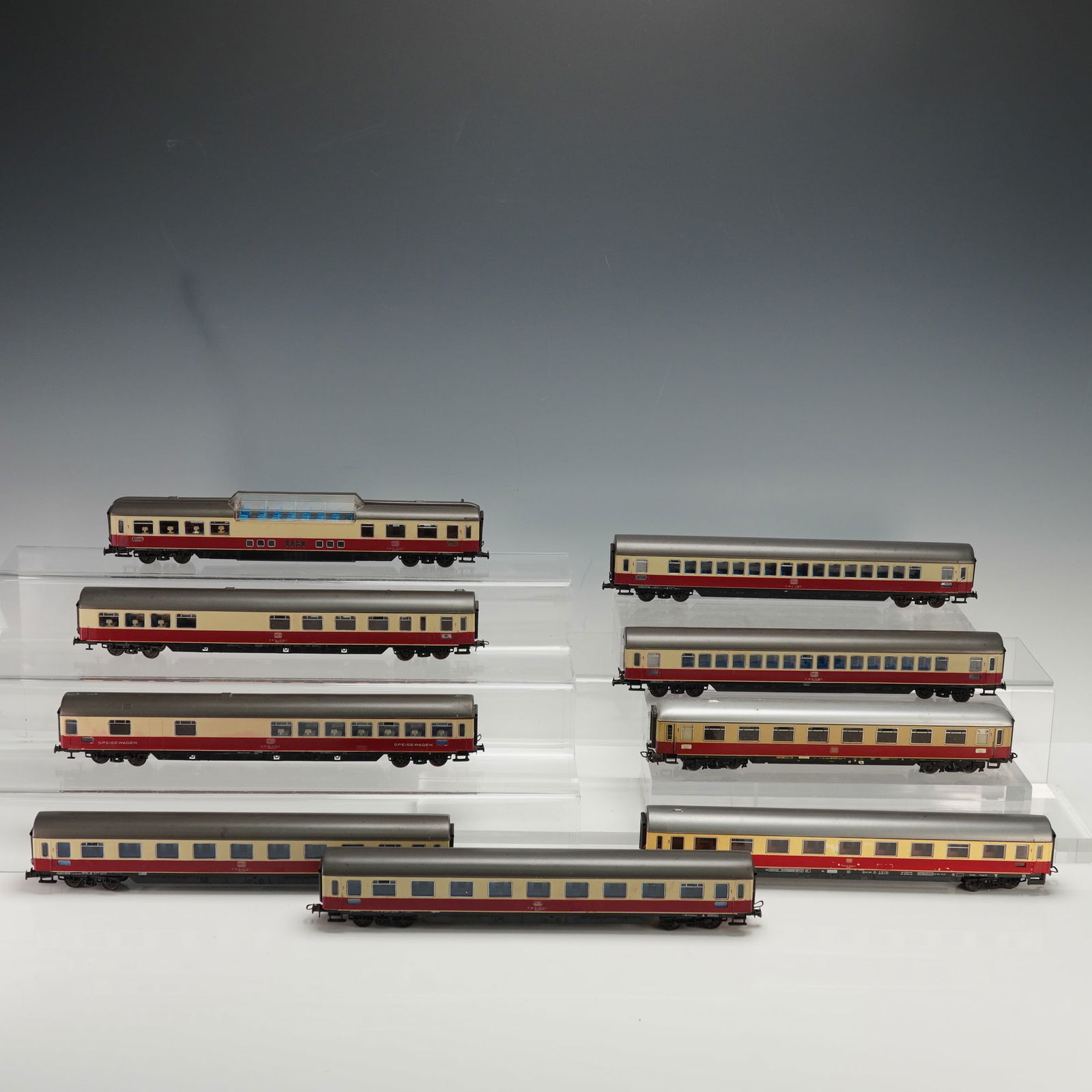 9pc Roco Deutsche Bundesbahn Passenger Car Collection: A collection of nine scale toy trains presenting the Deutsche Bundesbahn express passenger travel. The assortment includes a diverse range of coaches such as dining and sleeping cars, along with a pan