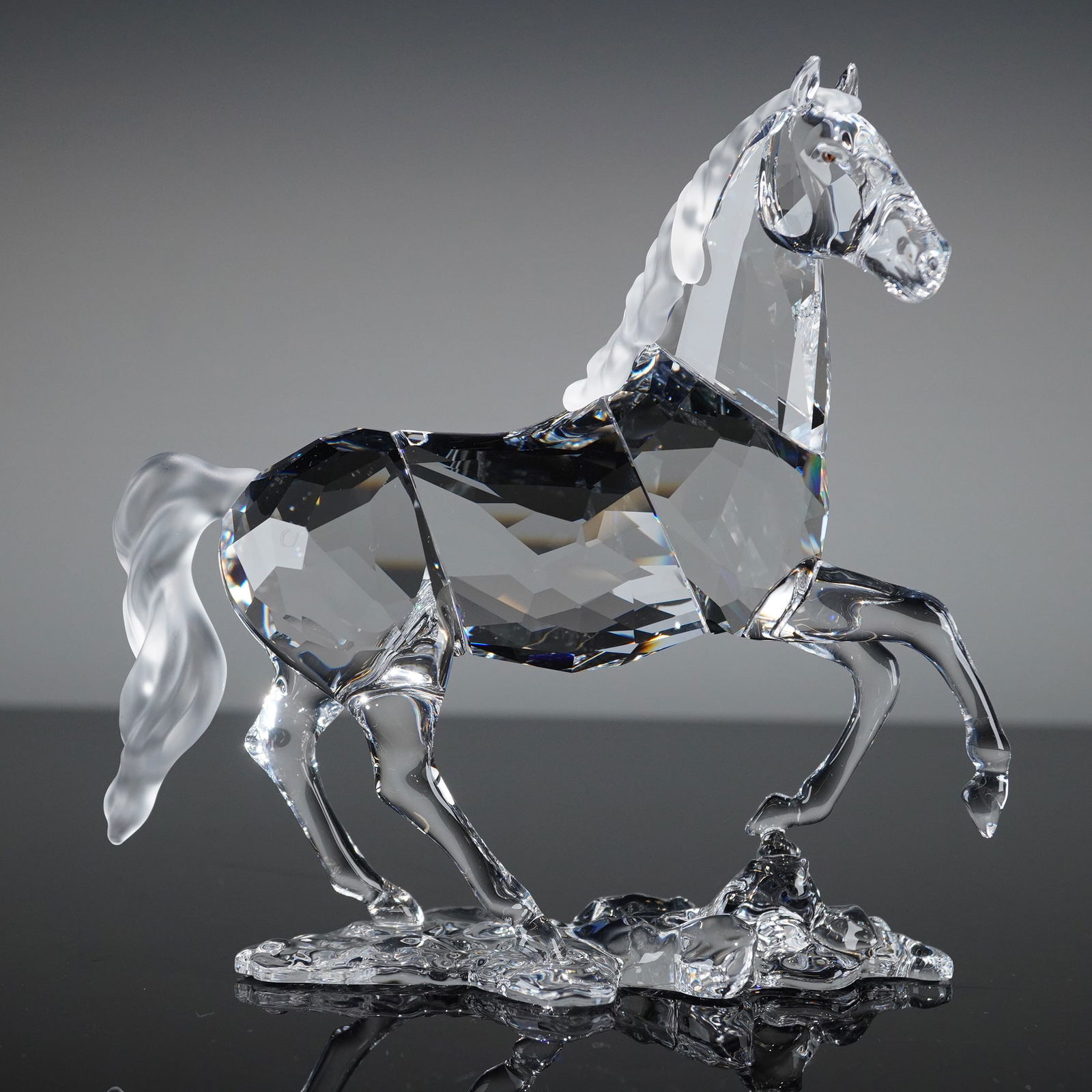 Swarovski Crystal Stallion Horse Figurine 898508: A crystal sculpture figurine by Swarovski depicting a rearing stallion horse, with the body executed in clear, fully faceted crystal, providing high reflectivity. The mane and tail are rendered in con