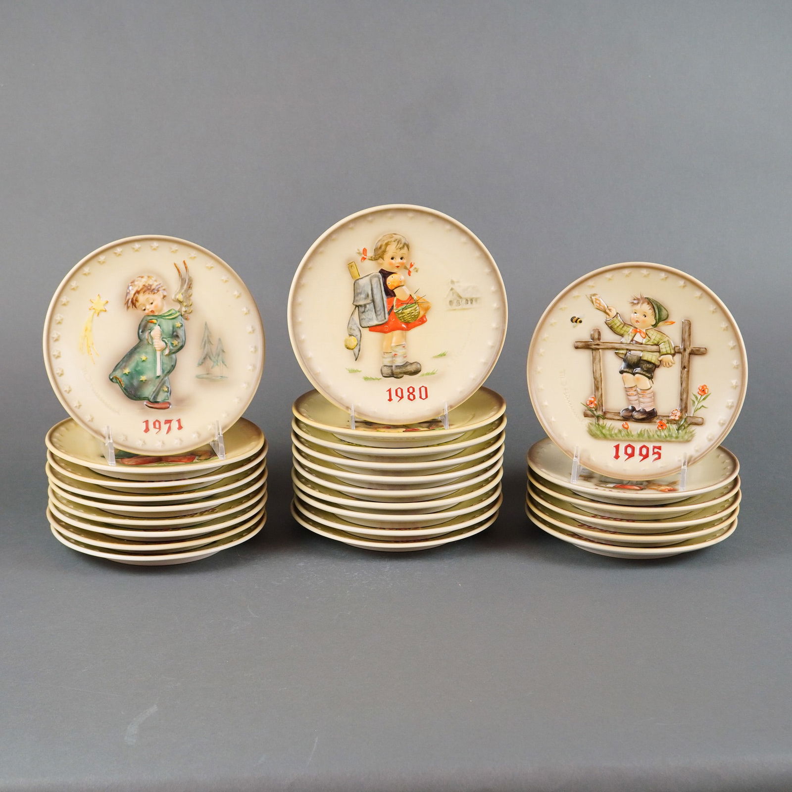 25 Goebel Hummel Annual Collector Plates 1971-1995 Bas Relief: A large collection of M.J. Hummel Annual Collector Plates produced by Goebel. The lot contains 25 plates, including the core annual edition series spanning 1971 to 1995 with boxes. The plates are cera