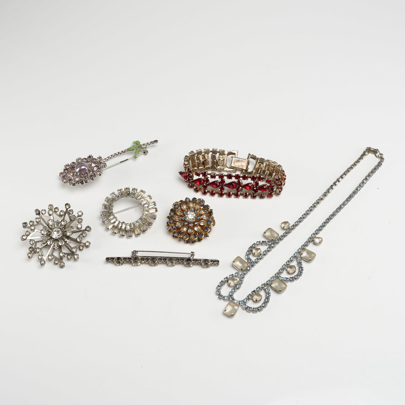 A Collection of Seven Pieces of Vintage Costume Jewelry: A collection of seven pieces of vintage costume jewelry, comprising five brooches, one articulated bracelet, and one necklace. The lot features various base metal constructions in both gold-tone and s