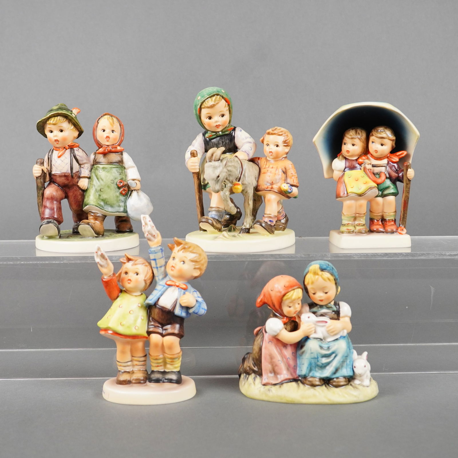 5 Goebel Hummel Figurines incl. Going Home & Stormy Weather: A collection of five German porcelain figurines manufactured by Goebel, commonly known as Hummel figures. These pieces are executed in glazed ceramic and hand-painted, depicting idealized scenes of ch