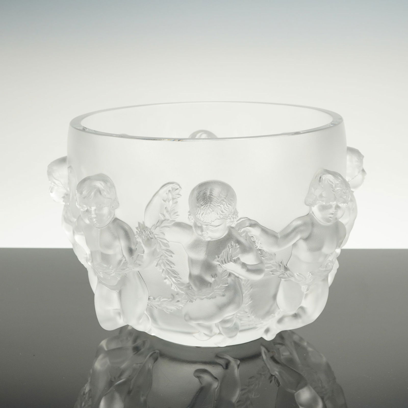 Lalique Crystal Luxembourg Cherub Bowl: This is a Lalique Frosted Crystal Luxembourg Cherub Bowl. The cylindrical vessel is crafted from clear and molded satin, consistent with the material and technique used for Lalique Frosted Crystal ite