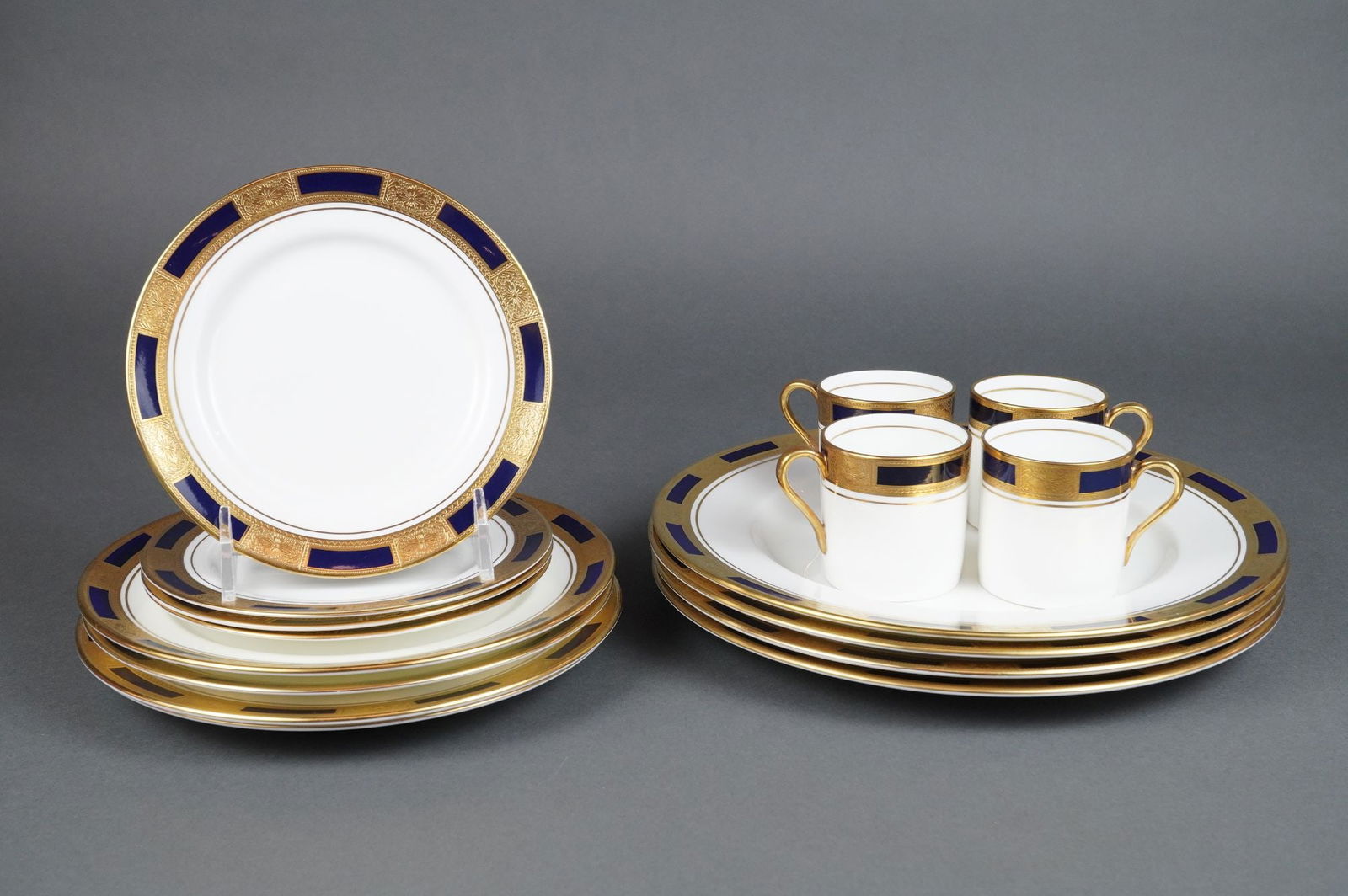 Coll. of 16 Pieces of Aynsley Empress Cobalt Bone China Set for Four: A collection of 16 pieces of Aynsley Fine English Bone China in the Empress Cobalt pattern, comprising a set for four. The service includes four cylindrical handled cups and twelve circular plates or