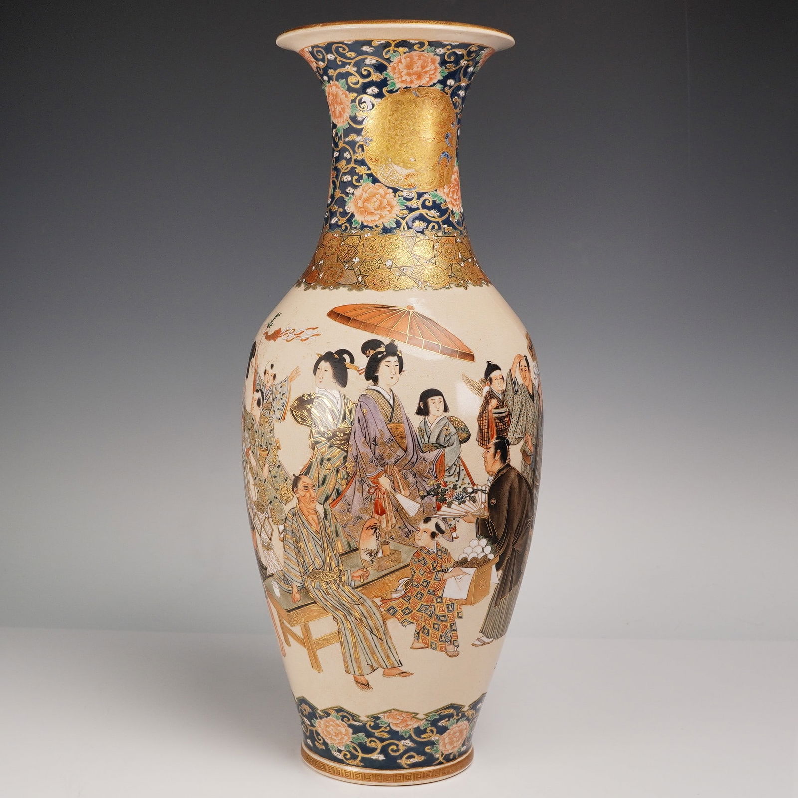 Japanese Festival Scene Satsuma Vase: Japanese Satsuma vase featuring an elaborate festival scene. The tall, slender vessel has a wide flared rim and is decorated with hand-painted figures in traditional attire engaged in various activiti