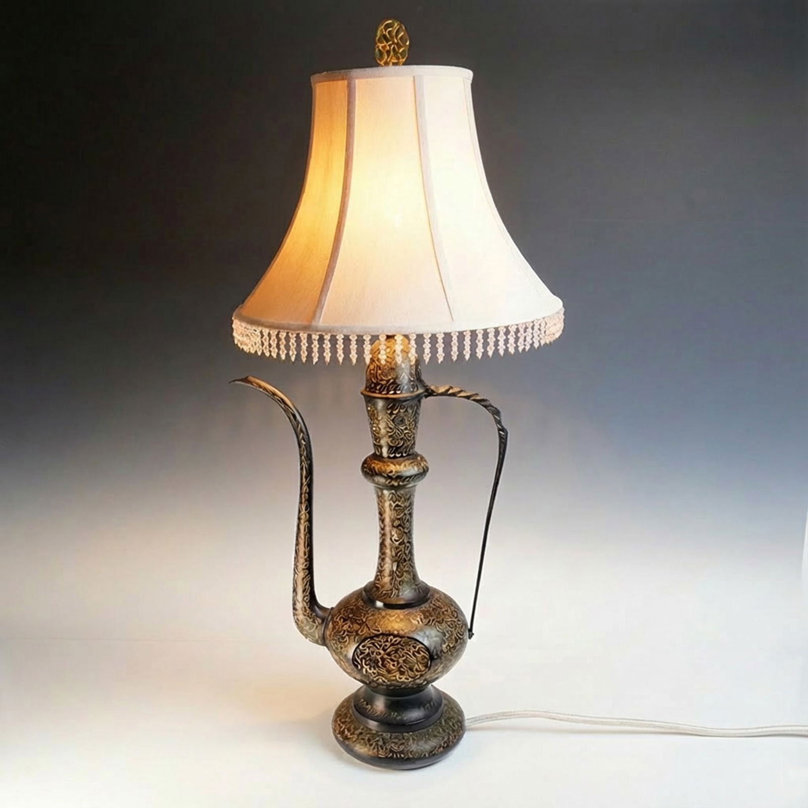 1960s Indian Koftgari Brass Jeannie Table Lamp: A Mid-Century Modern Indian table lamp, circa 1960s, identified as a 'Jeannie Lamp' due to its distinctive ewer or pitcher-like form. The base is constructed from metal, likely brass or a copper alloy
