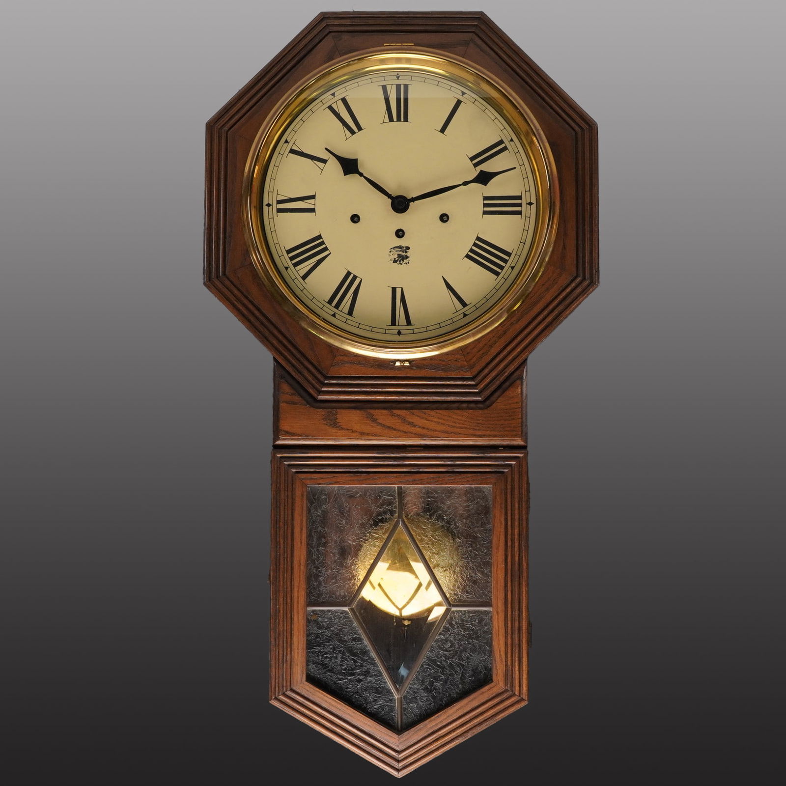 San Francisco Clock Co. Oak Wall Clock with Pendulum: A vintage oak wall clock by the San Francisco Clock Company, featuring an octagonal face and elongated case with decorative leaded glass door revealing a brass pendulum. The clock face bears Roman num