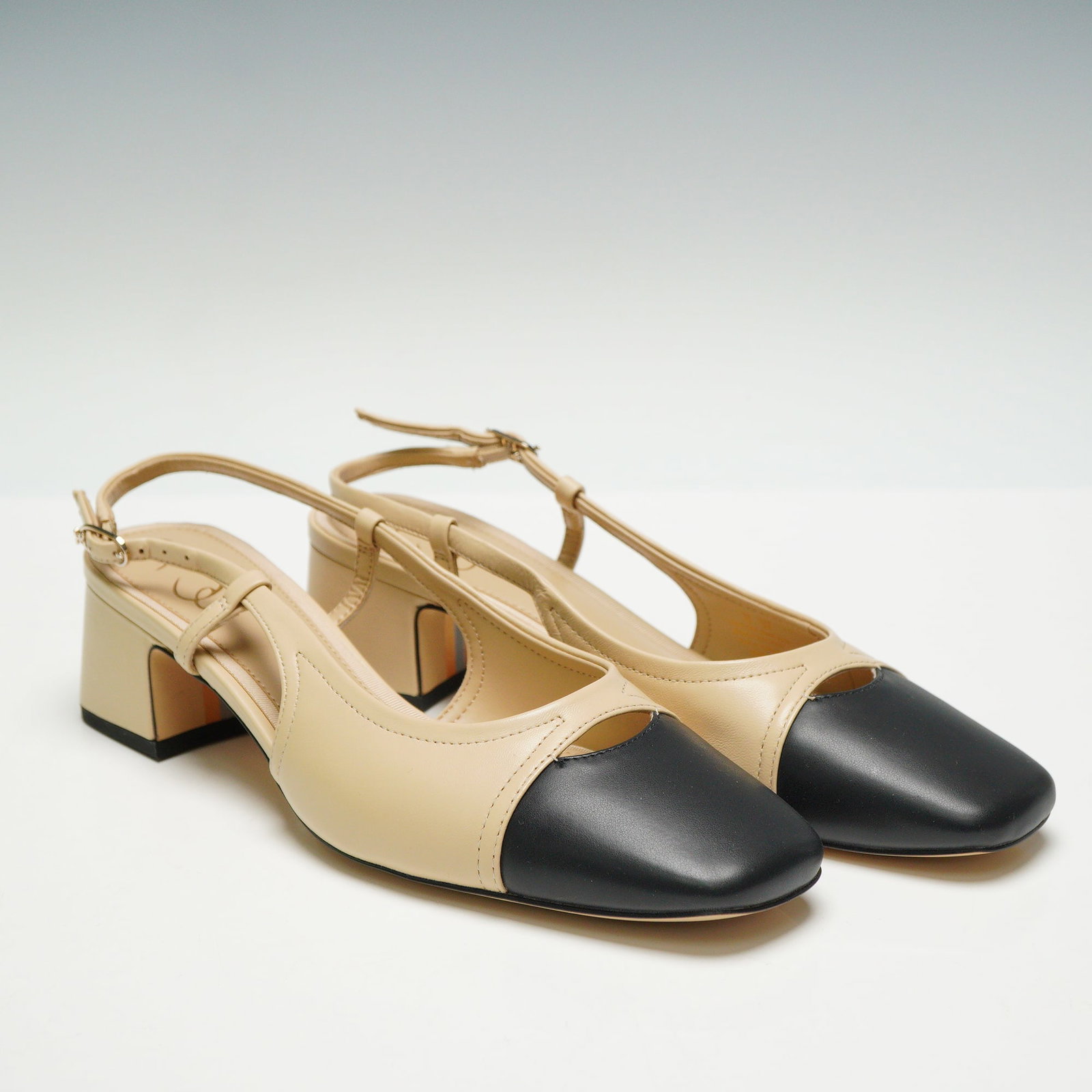 A Pair of Sam Edelman Tarra Slingback Heels, Sand: A pair of Sam Edelman Tarra slingback heels with smooth beige uppers, black square cap toes, and low stacked look block heels. The outsoles feature stylized S and E branding with orange and grey accen