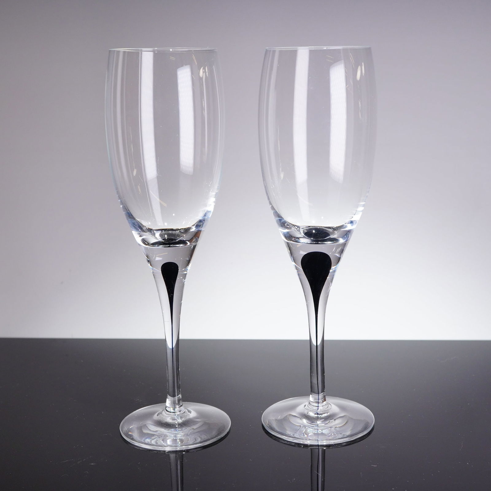 A Pair of Orrefors Intermezzo Black White Wine Glasses by Erika Lagerbielke: A pair of modern crystal white wine glasses designed by Erika Lagerbielke for Orrefors in the Intermezzo Black patern. Each glass is executed in clear colorless crystal featuring a tall, narrow bowl a