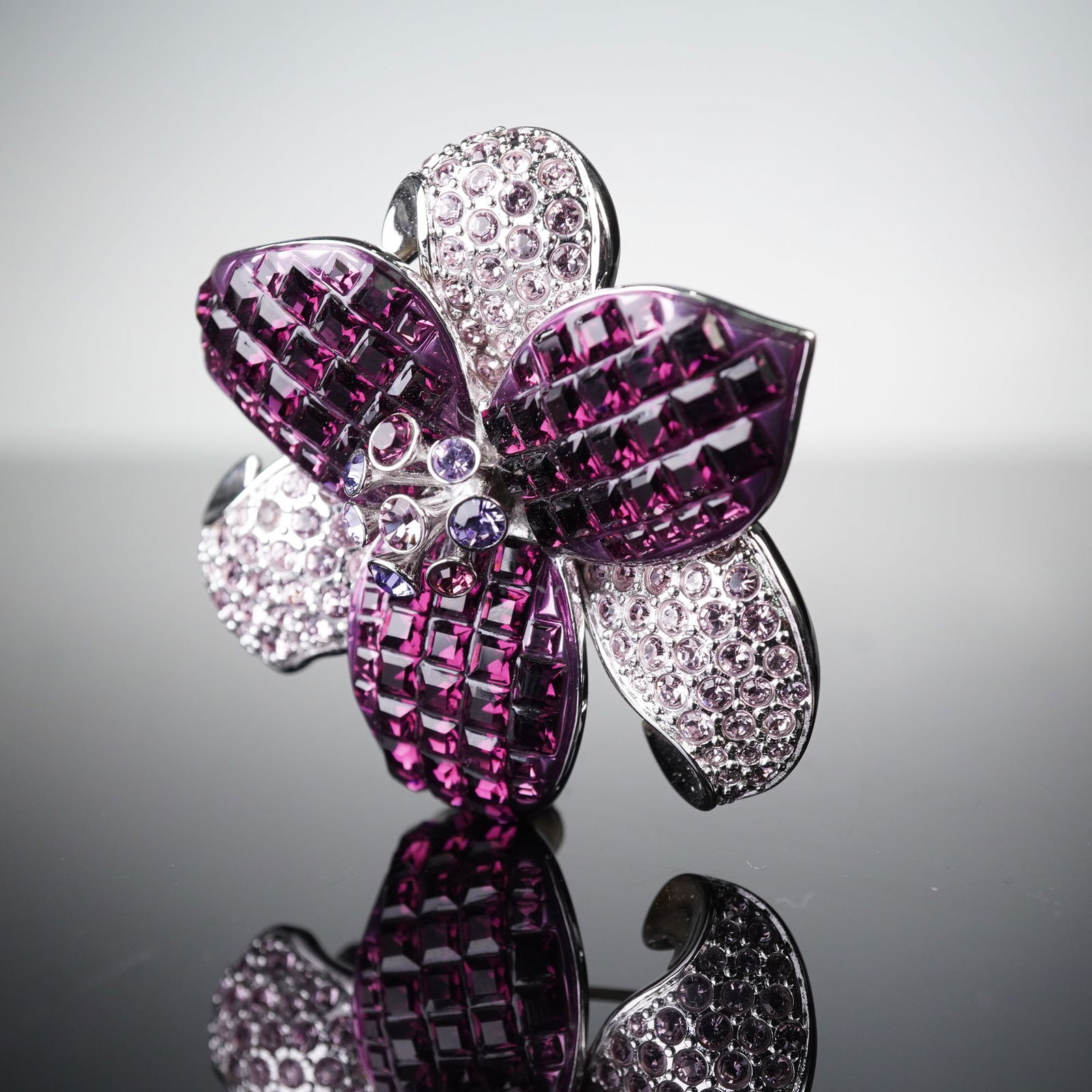 Swarovski Silver-Tone Purple Crystal Pave Flower Brooch: A contemporary Swarovski floral brooch featuring a prominent five-petaled flower design in a silver-toned metal setting. Several petals are entirely paved with numerous square-cut dark purple crystals
