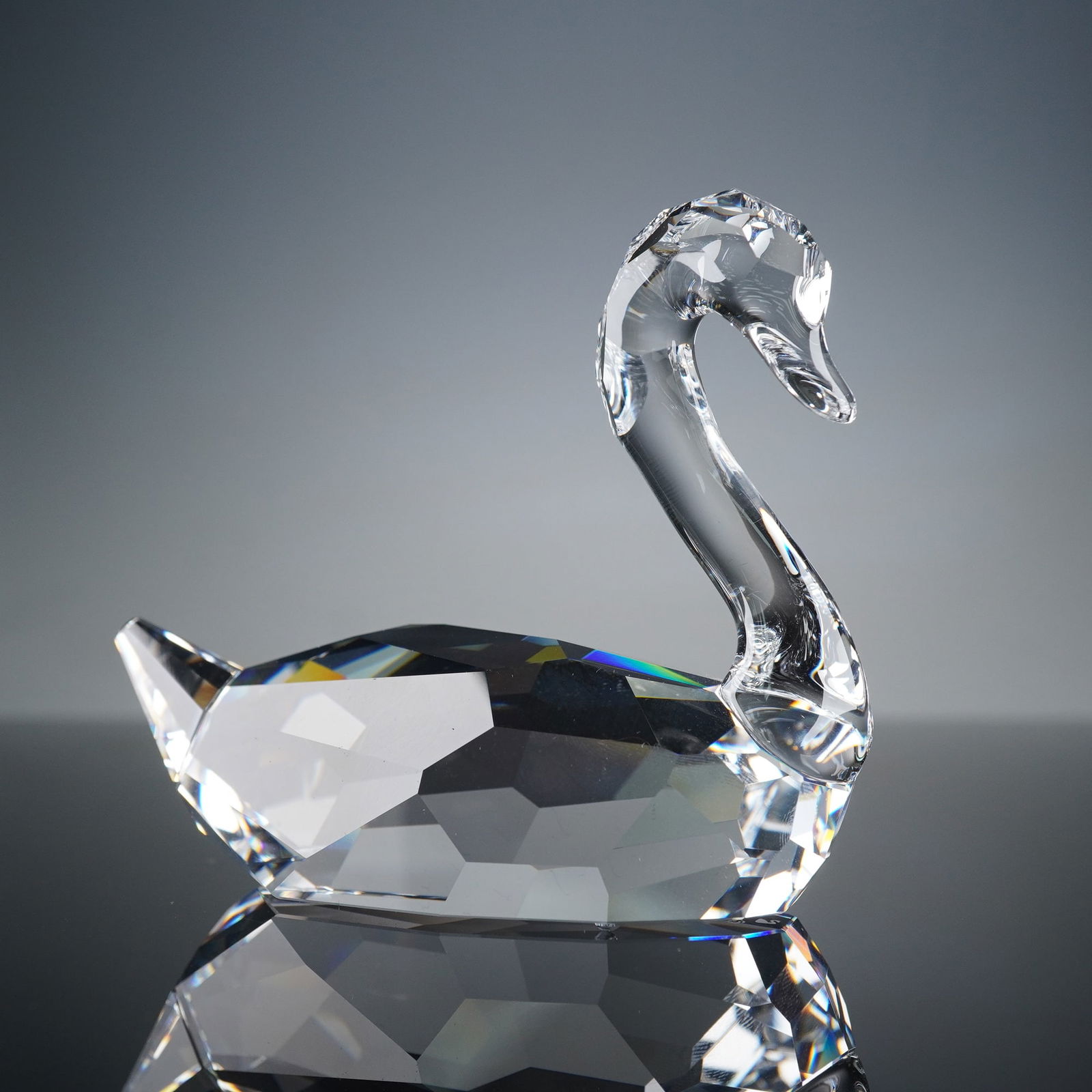Swarovski Signum Swan Crystal Figurine: A Swarovski Signum Swan crystal figurine. This modern, faceted crystal figurine depicts a swan in a clear, geometric sculptural style, exhibiting high light refraction and rainbow light dispersion acr