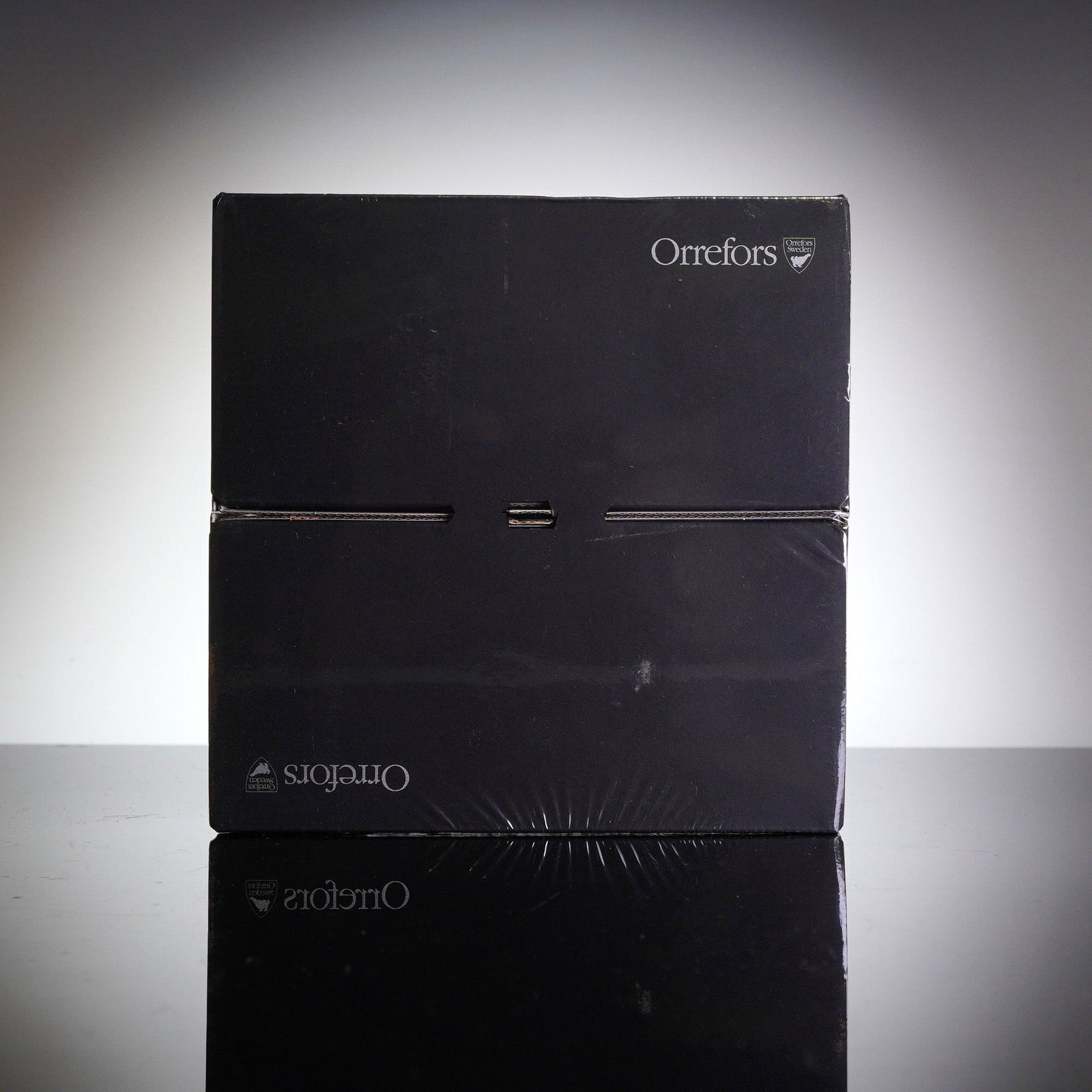 A Pair of Orrefors Intermezzo Blue Crystal Tumblers, Sealed in Box: A pair of Orrefors crystal tumblers in the Intermezzo Blue patern, presented in their original factory-sealed black cardboard presentation box. The packaging is rectangular, featuring the Orrefors nam
