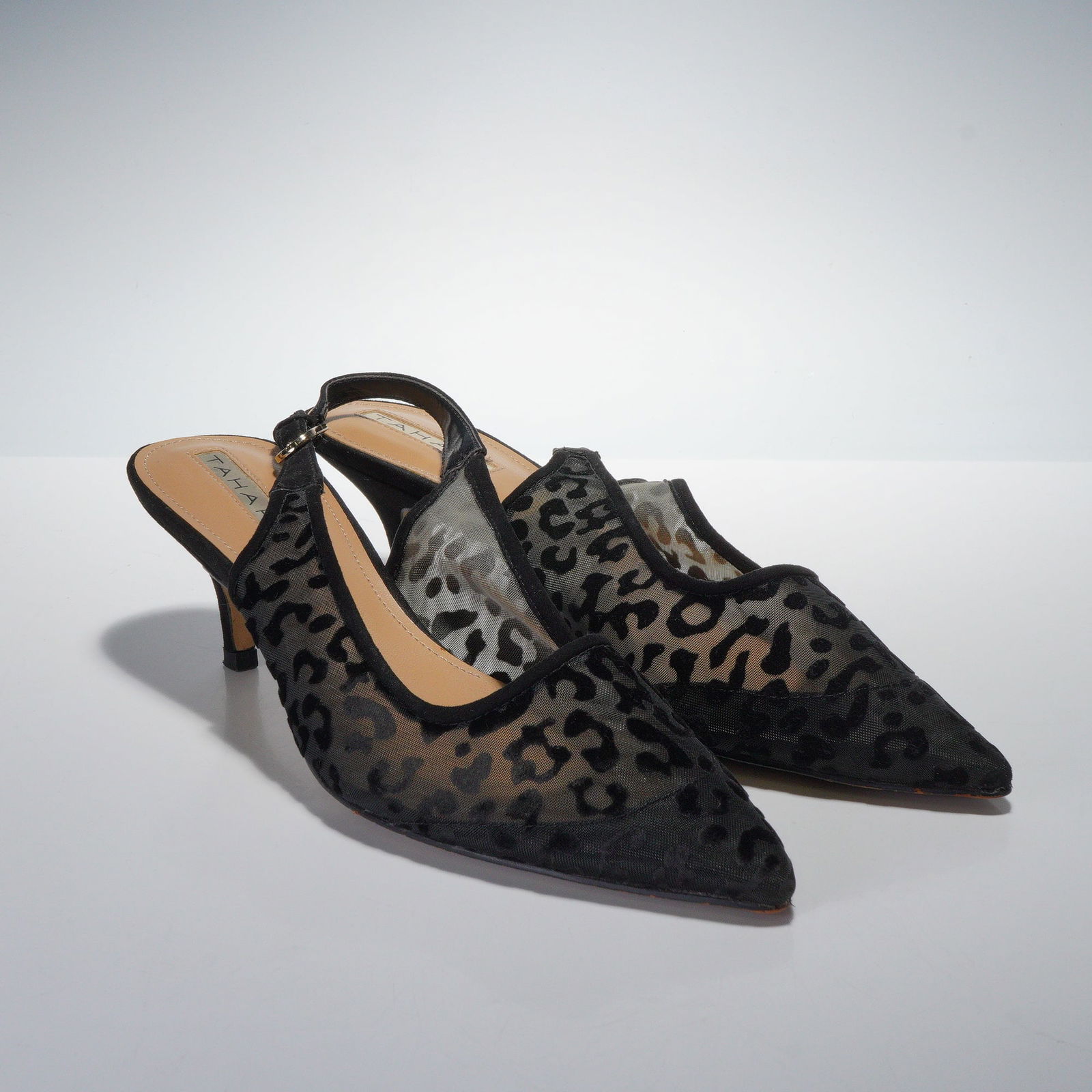 A Pair of TAHARI Womens Black Mesh Leopard Print Slingback Kitten Heels: A pair of contemporary womens slingback heels by TAHARI. These shoes feature a pointed toe and a low, slender kitten heel. They are primarily constructed from black sheer mesh textile with a flocked v
