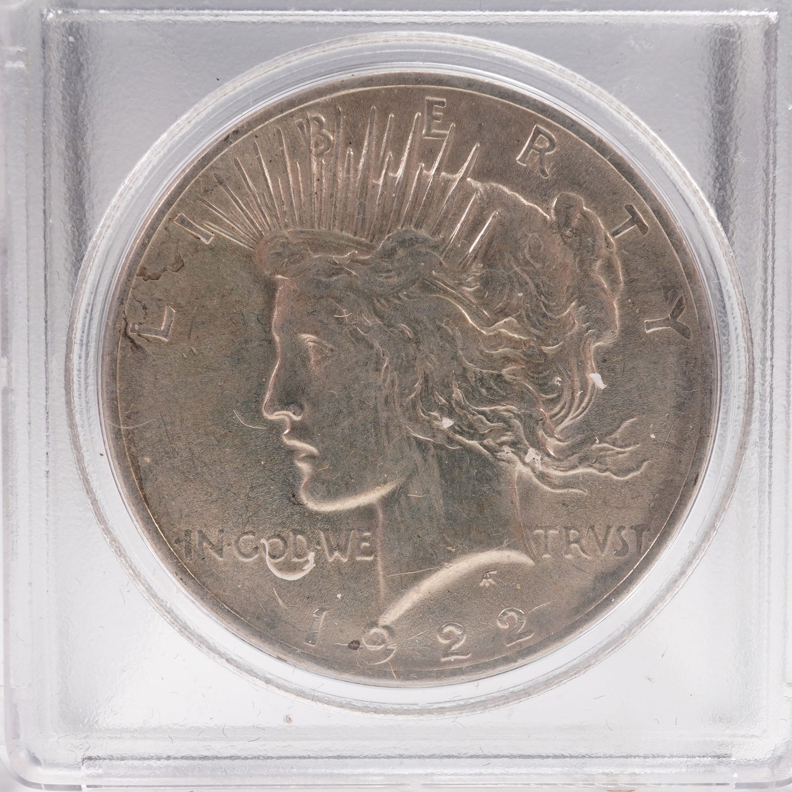 1922 Peace Dollar Silver Coin: The 1922 Peace Dollar is struck in .900 fine silver. The obverse features a capped head of Liberty facing left, with a headband adorned with rays. The Latin inscriptions read LIBERTY, IN GOD WE TRVST,