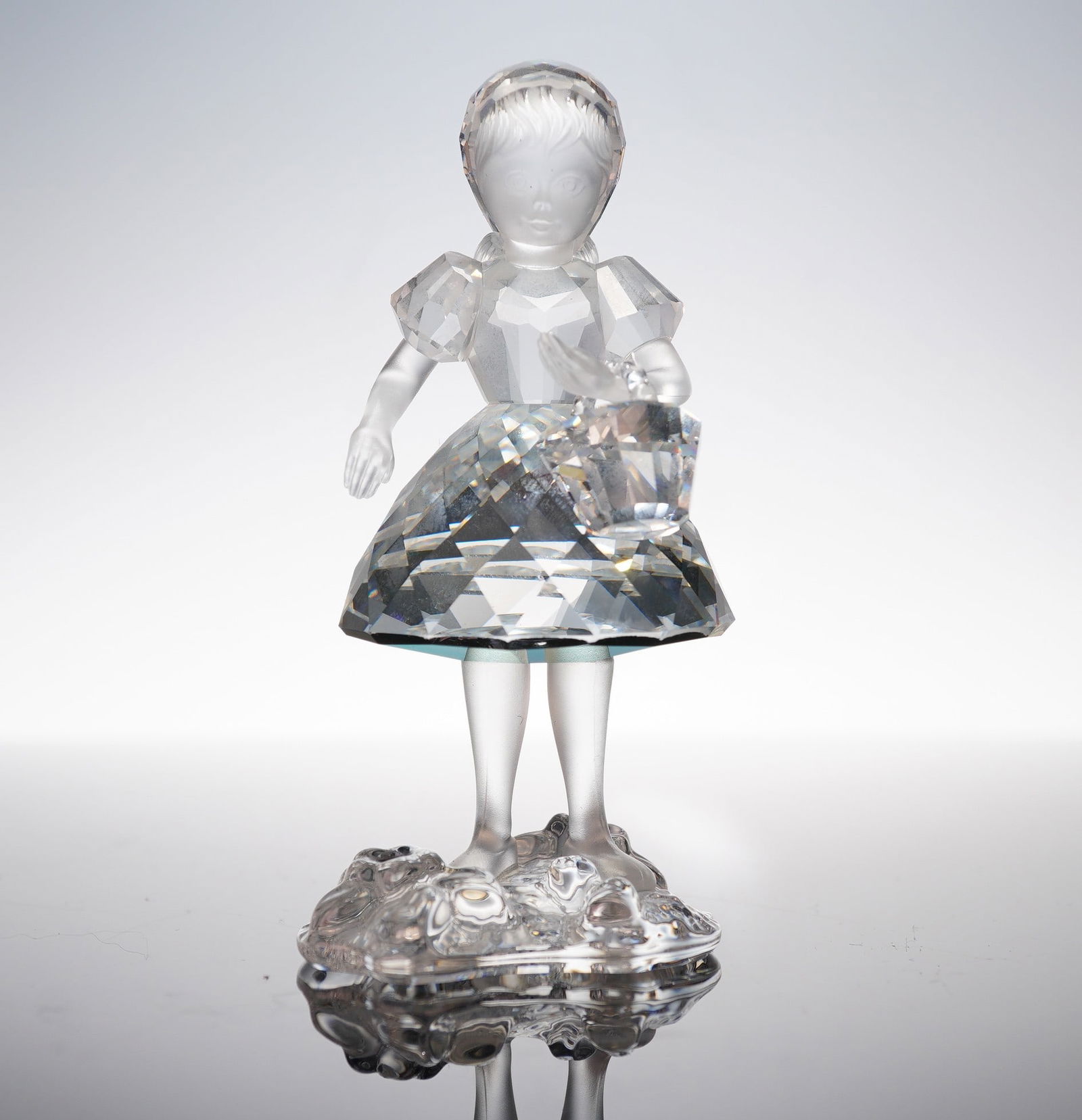 Swarovski Crystal Fables & Fairy Tales Figurine, Red Riding Hood: A Swarovski figurine depicting Red Riding Hood from the Fables & Fairy Tales series, model 191695. Clear faceted crystal dress and basket; frosted crystal head, arms, and legs. Stands on a textured ba