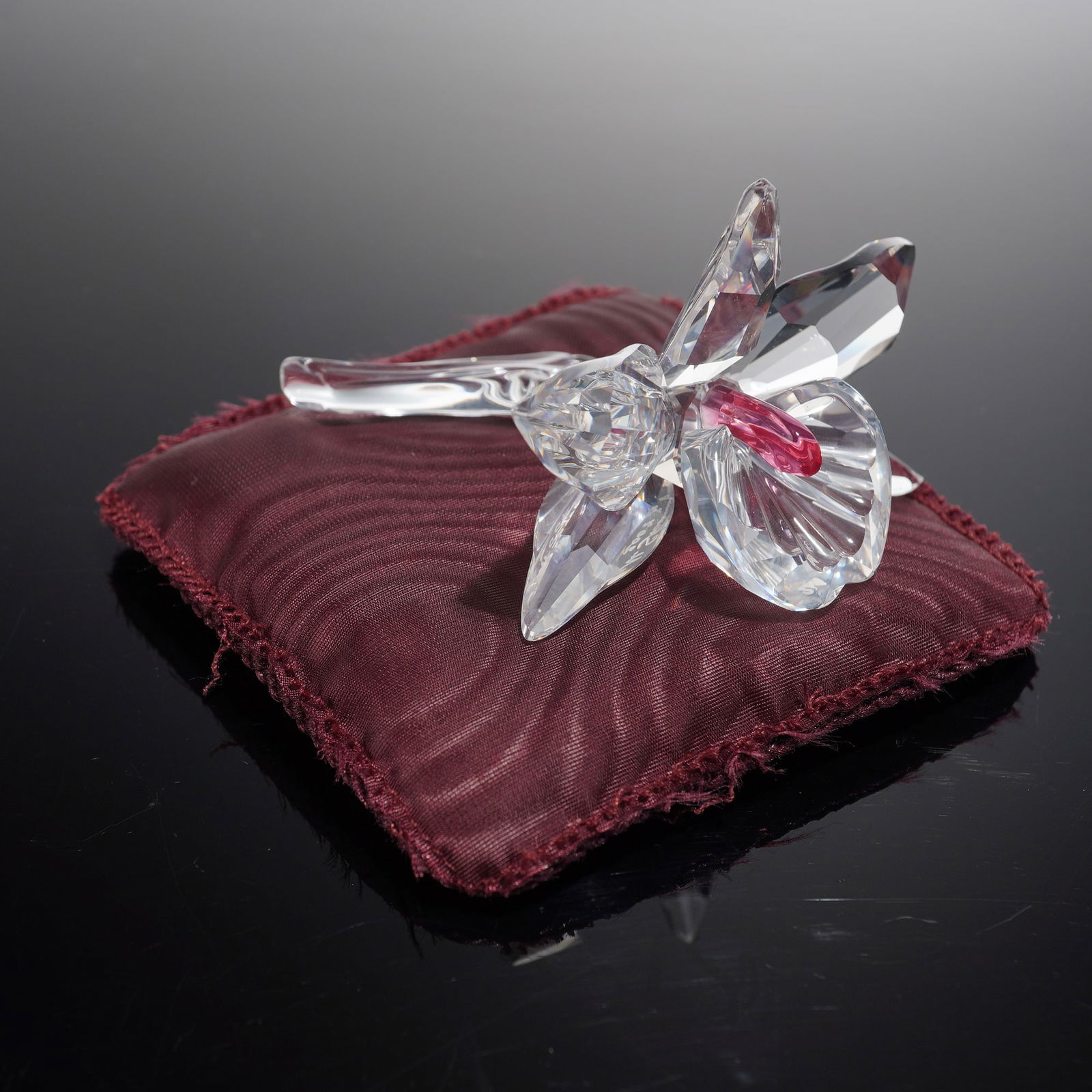 Swarovski Crystal Figurine Pink Orchid Signed By Michael Stamey With Box: Swarovski crystal items identified as the Orchid Pink-Dark Centre figurine, model number 200287, and signed by the artist, Michael Stamey. The set includes the crystal flower figurine, a display cushi