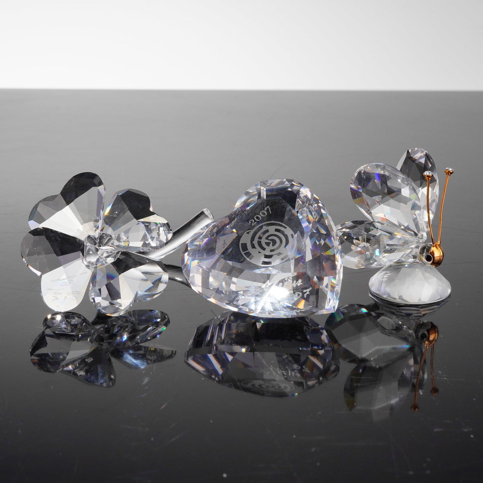 3pc Signed Swarovski Crystal Figures, including SCS 2007 Event Heart: A collection of three items comprising three colorless faceted Swarovski crystal figurines and three associated cylindrical presentation boxes. The figures include a signed SCS Event Heart (896979) by