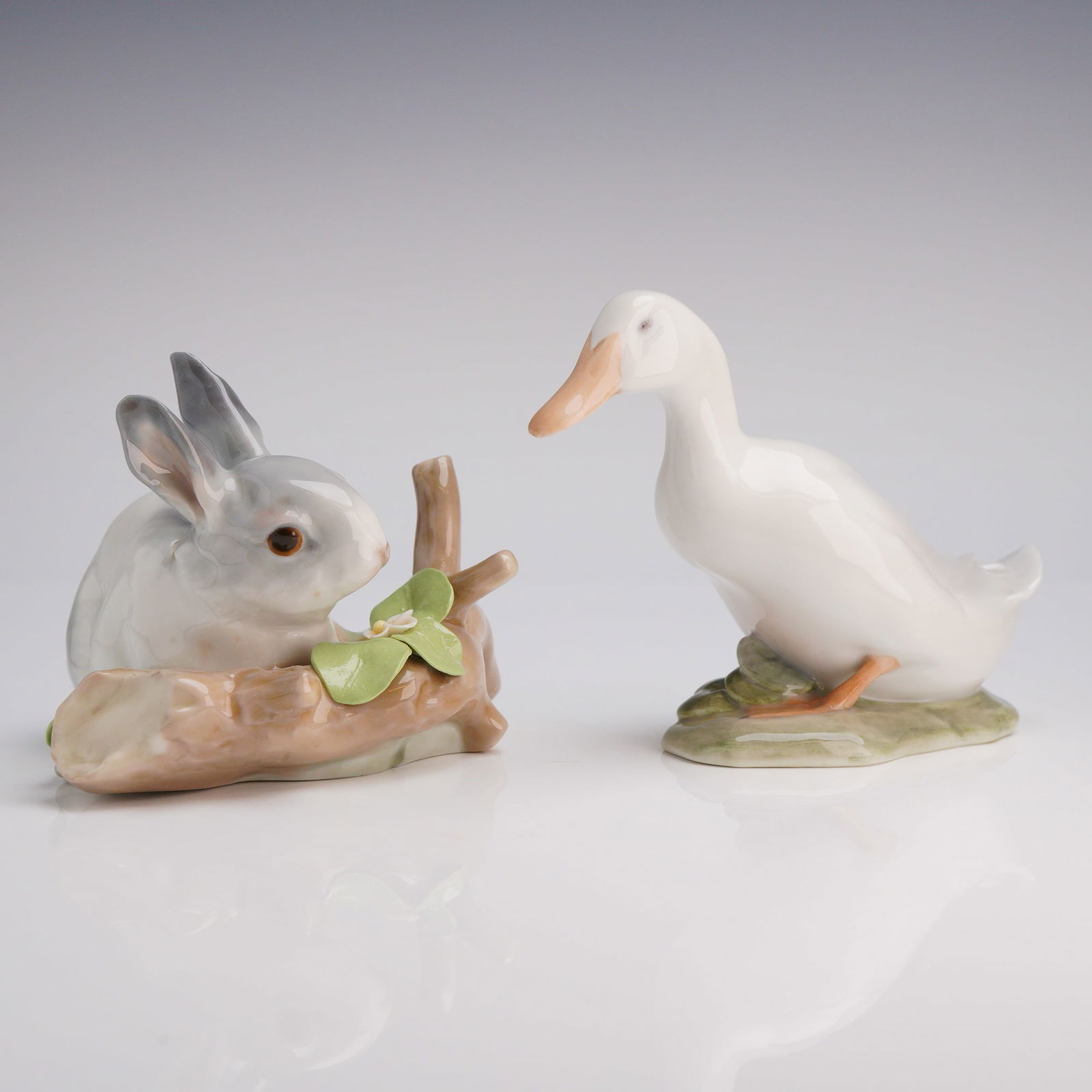 2pc Lladro and Royal Copenhagen Figurine, Rabbit Eating & Duck: The lot consists of two glazed porcelain animal figurines from different European manufacturers. The first item is a Lladro figurine titled "Rabbit Eating," number 4773. This piece depicts a gray and