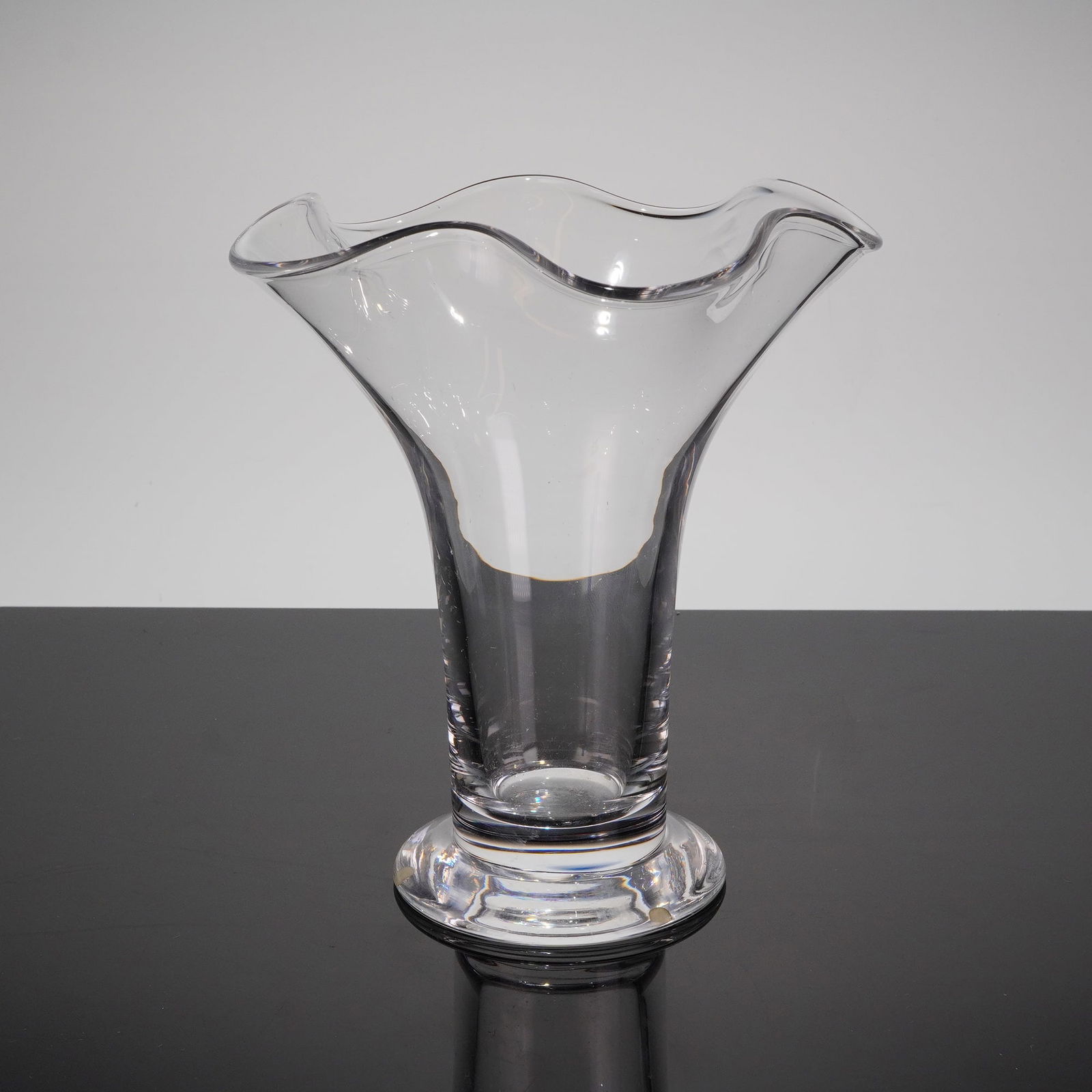 Orrefors Chanterelle Wave Form Vase by Anne Nilsson: A single Orrefors Chanterelle vase, designed by Anne Nilsson (b. 1953). This clear colorless glass vessel features a heavy, footed base supporting a trumpet-shaped body that flares dramatically outwar