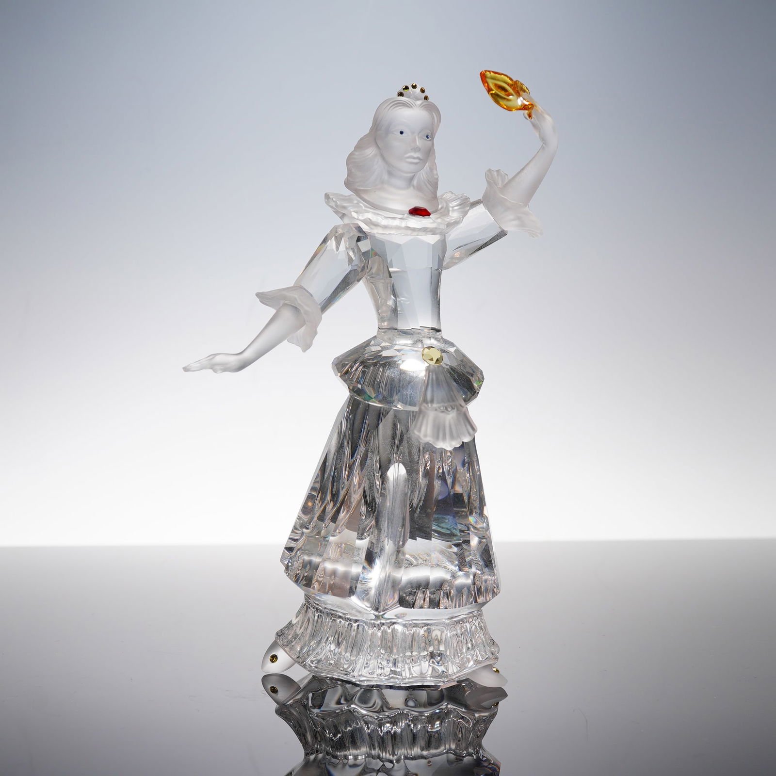 Swarovski SCS 2000 Crystal Masquerade Figurine, Columbine: A Swarovski SCS 2000 Annual Edition 'Masquerade Columbine' crystal figurine. Clear crystal with frosted accents, depicting a female figure in an elaborate gown and crown. Holds a gold and orange mask.