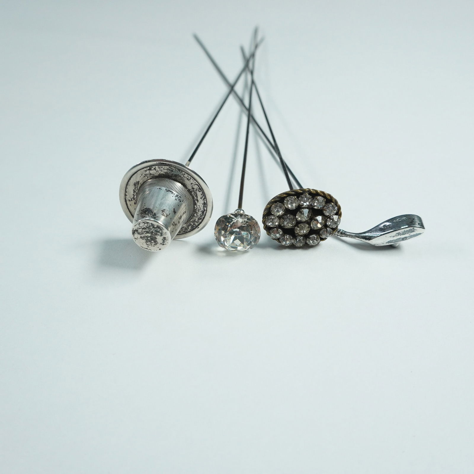 4pc Sterling Silver and Rhinestones Hatpins: This lot features a set of four hatpins with intricate designs, including a silver Welsh hat, a - marked silver, a rhinestone-encrusted flower - circa 1920, a crystal teardrop - circa 1920, and