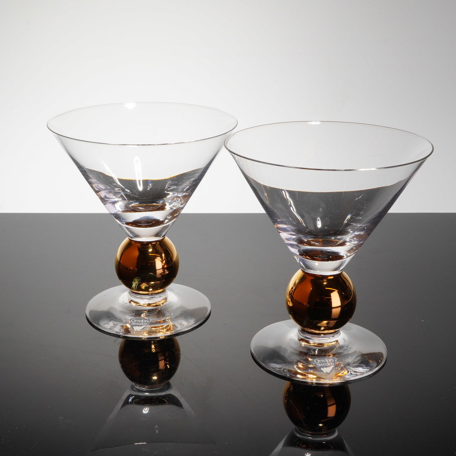 Pair of Orrefors Gunnar Cyren Nobel Crystal Martini Glasses: A pair of Orrefors crystal martini glasses from the Nobel series, designed by Gunnar Cyren. The 2pc set is constructed of clear colorless crystal. Each glass features a conical martini-shaped bowl