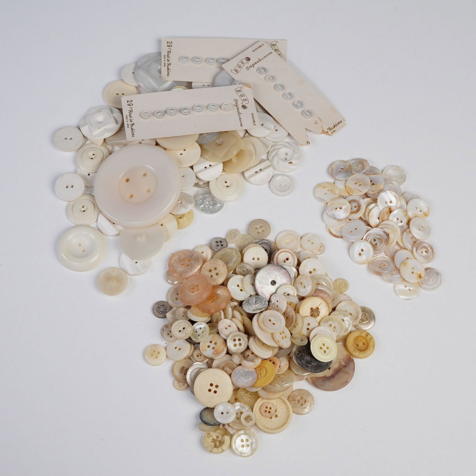 Large Collection of Ivory-Toned Buttons, Various Sizes: An extensive assortment of vintage and modern ivory-toned buttons in a variety of sizes, shapes, and finishes. The group includes both loose examples and several mounted on original cards, showcasing