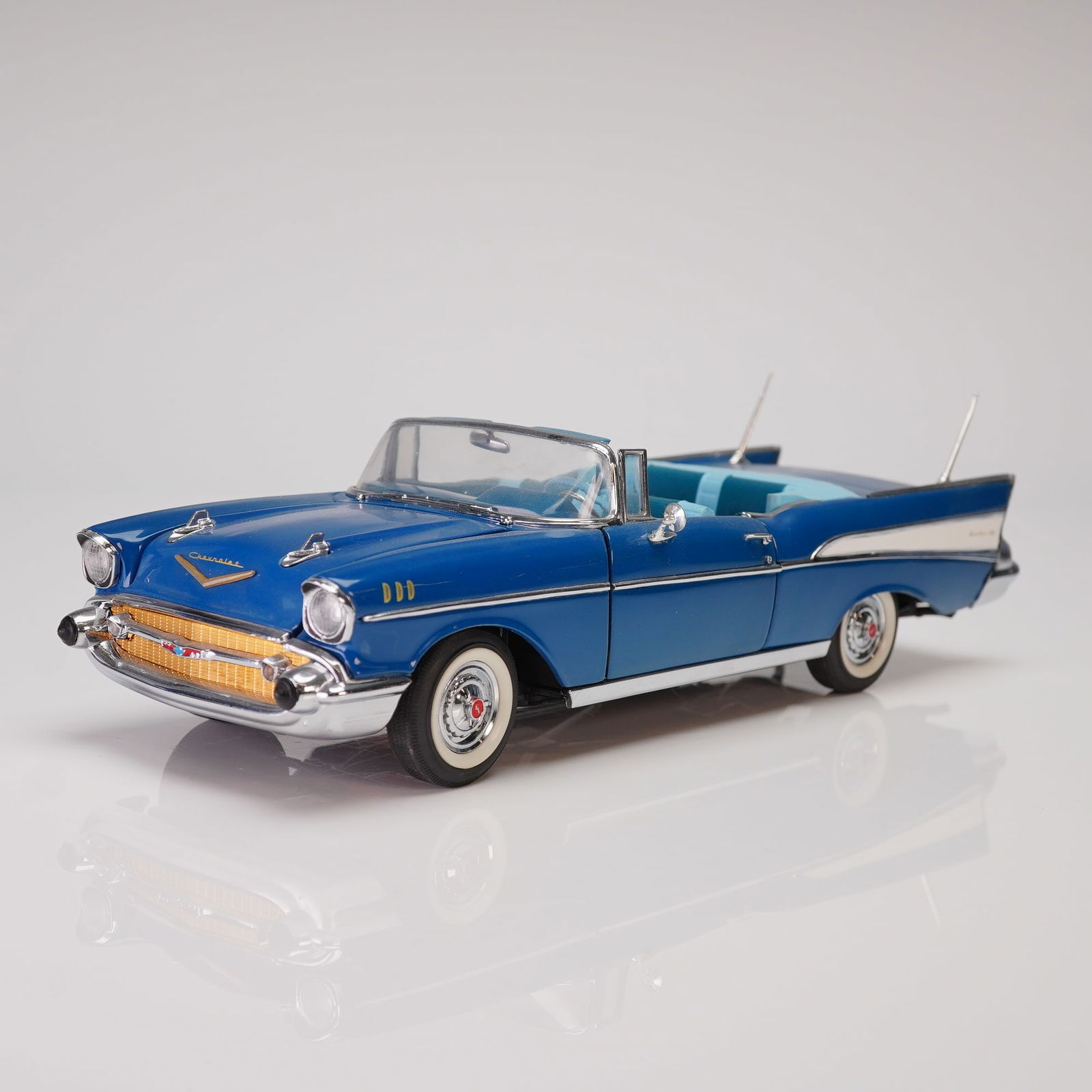 1957 Chevrolet Bel Air Convertible Model Die-Cast Replica: This lot presents a detailed die-cast scale model of the iconic 1957 Chevrolet Bel Air Convertible. Finished in a high-gloss deep blue exterior with contrasting white side trim and prominent chrome ac